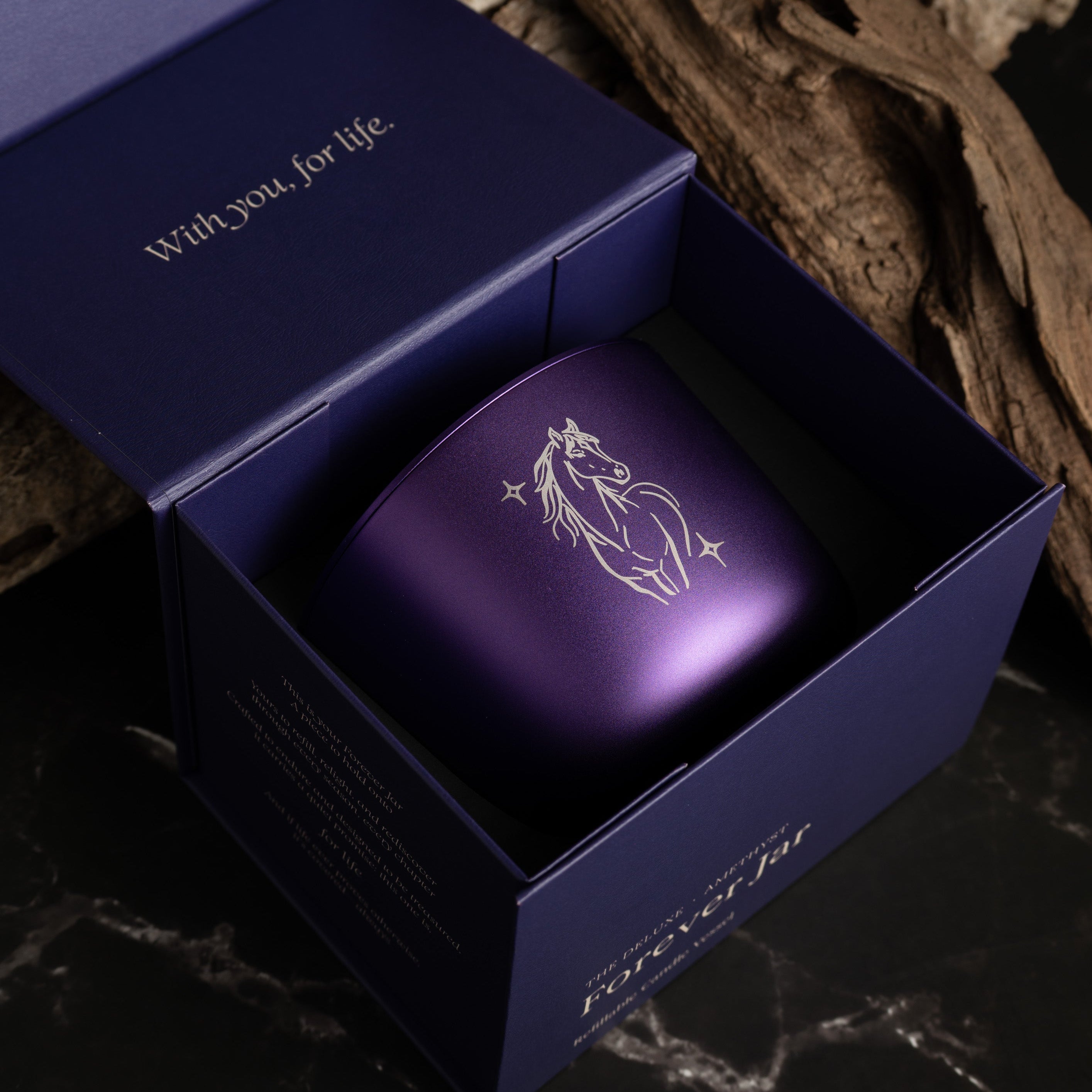 Purple candle in an open box with 'With you for life' text, on a dark textured background.