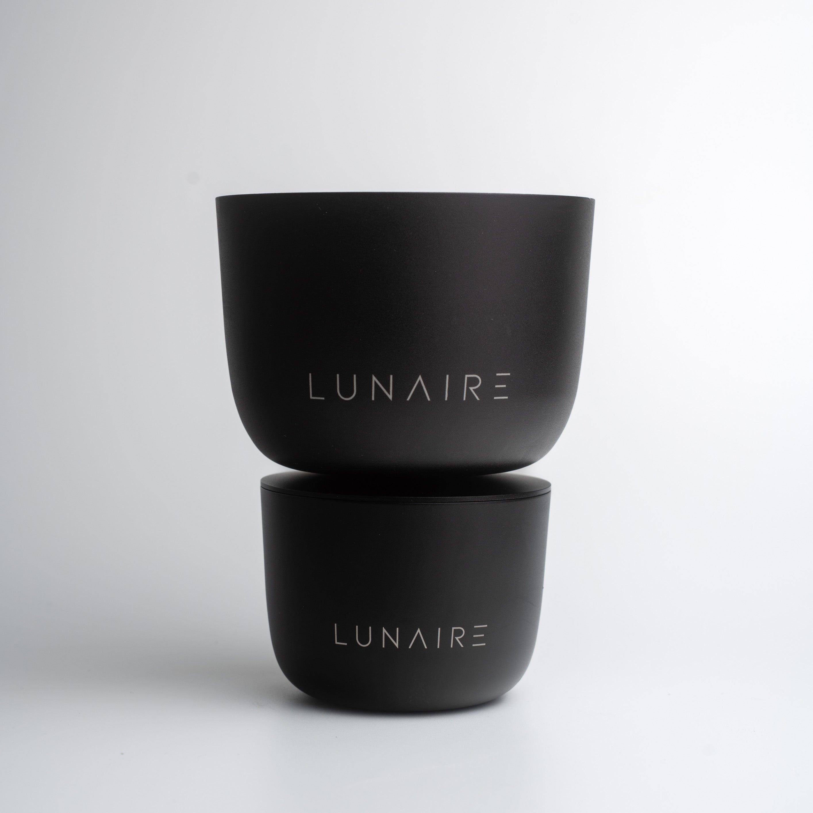 Two black aluminium forever candle jars with 'LUNAIRE' branding on a white background