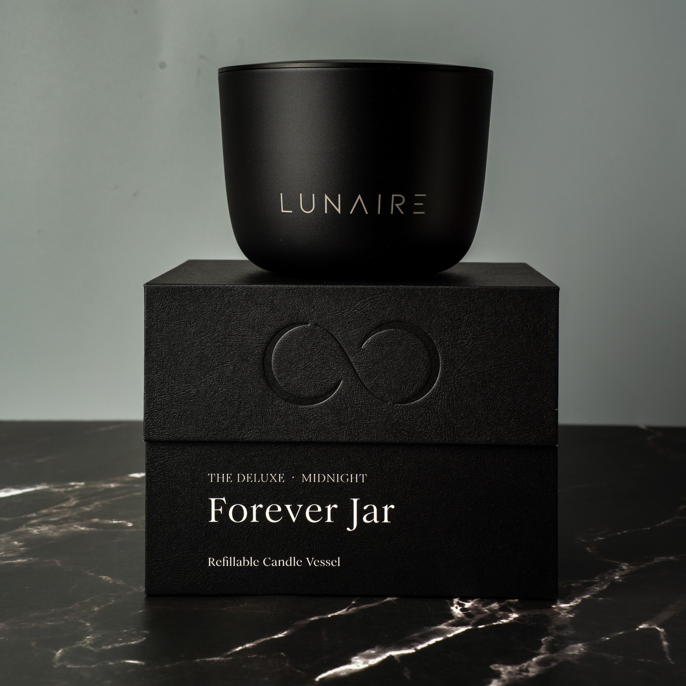 Black refillable candle jar labeled 'Lunaire' on a black box with 'Forever Jar' text against a gray background.
