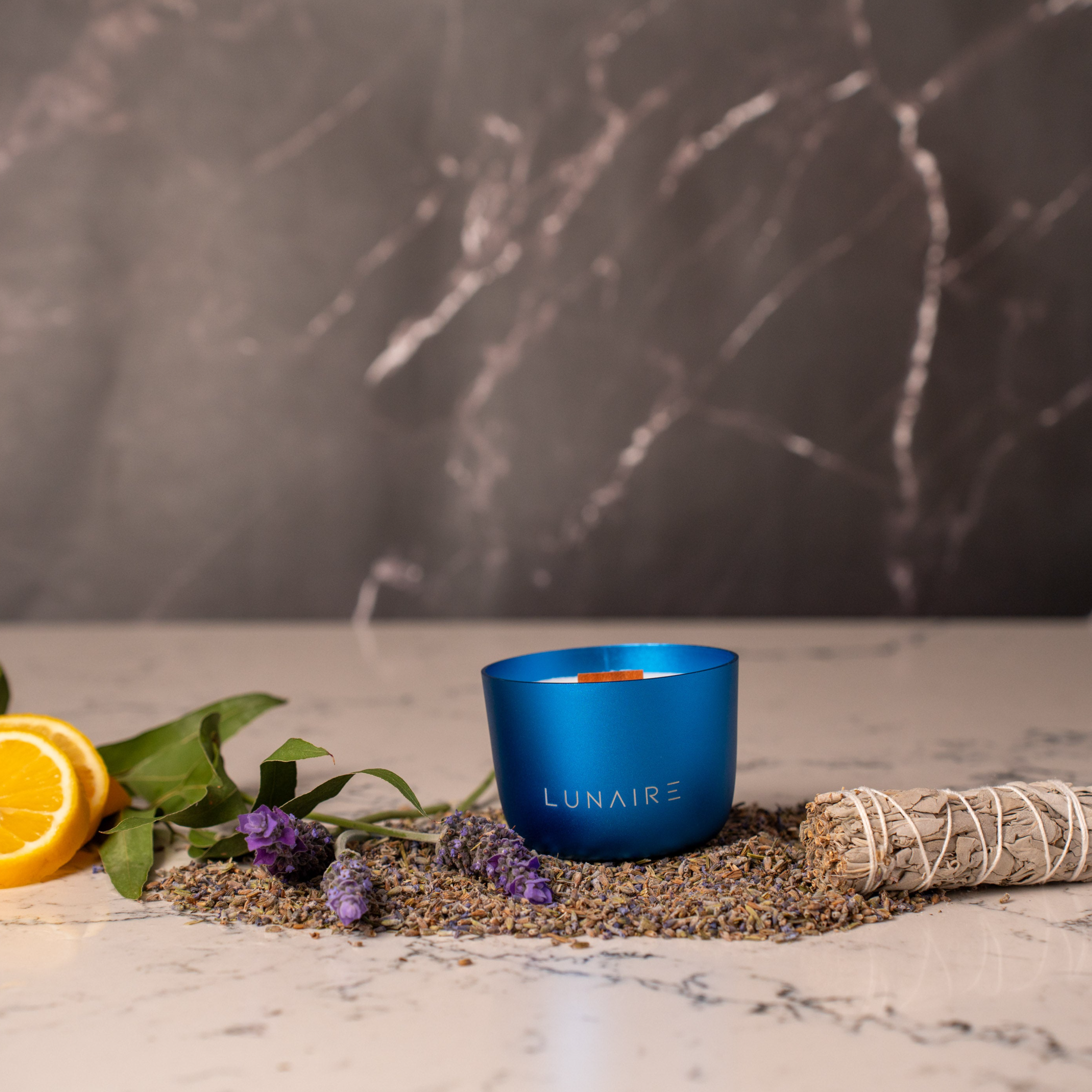 Blue Forever Jar Lunaire Candle Uranus Scent. Candle is on marbeled bench top with lavender, lemon , eucalyptus, and sage stick.
