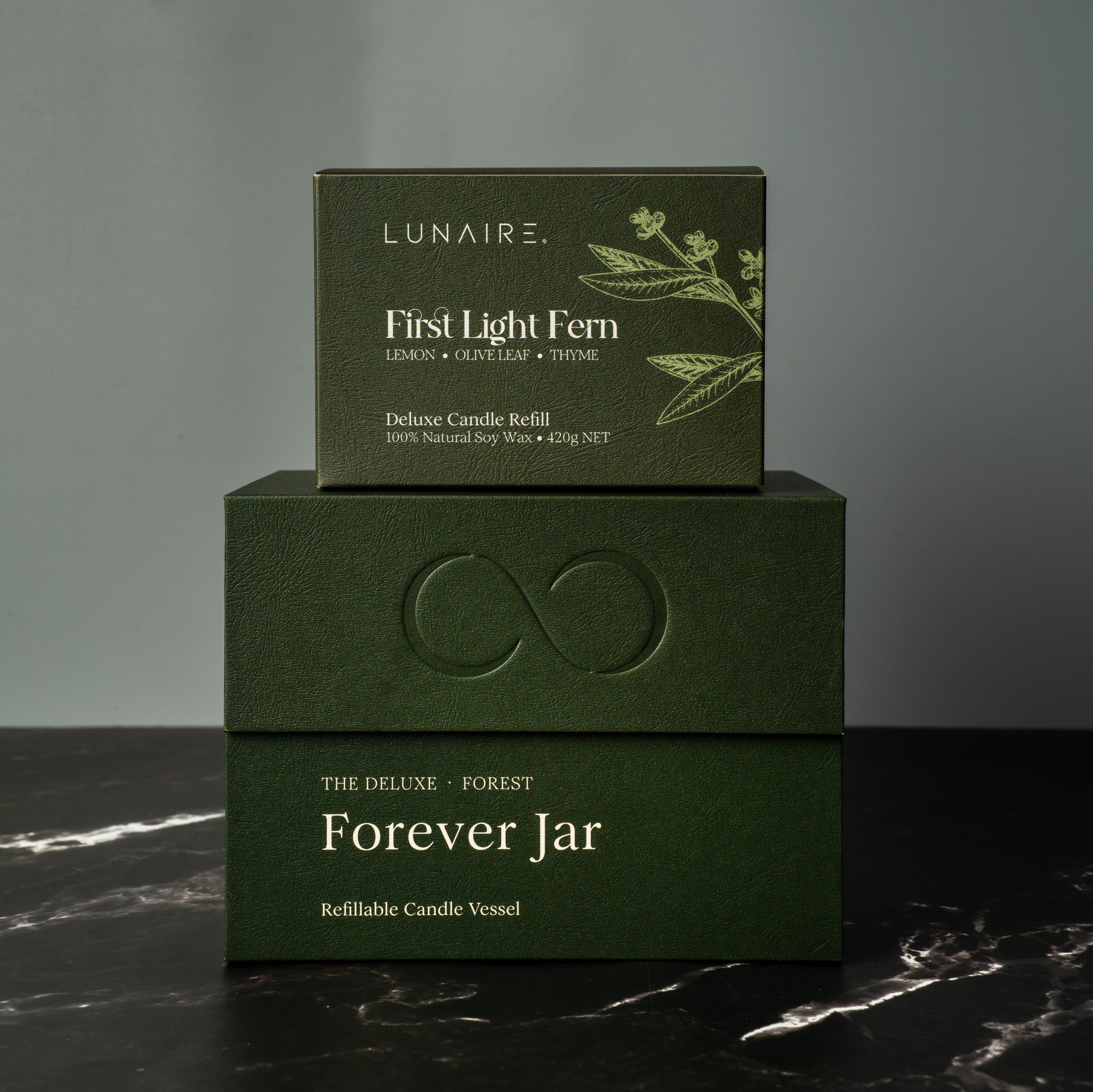 Two green boxes with 'Lunaire' branding on a dark marble surface. Luxury Candle Gift Set.