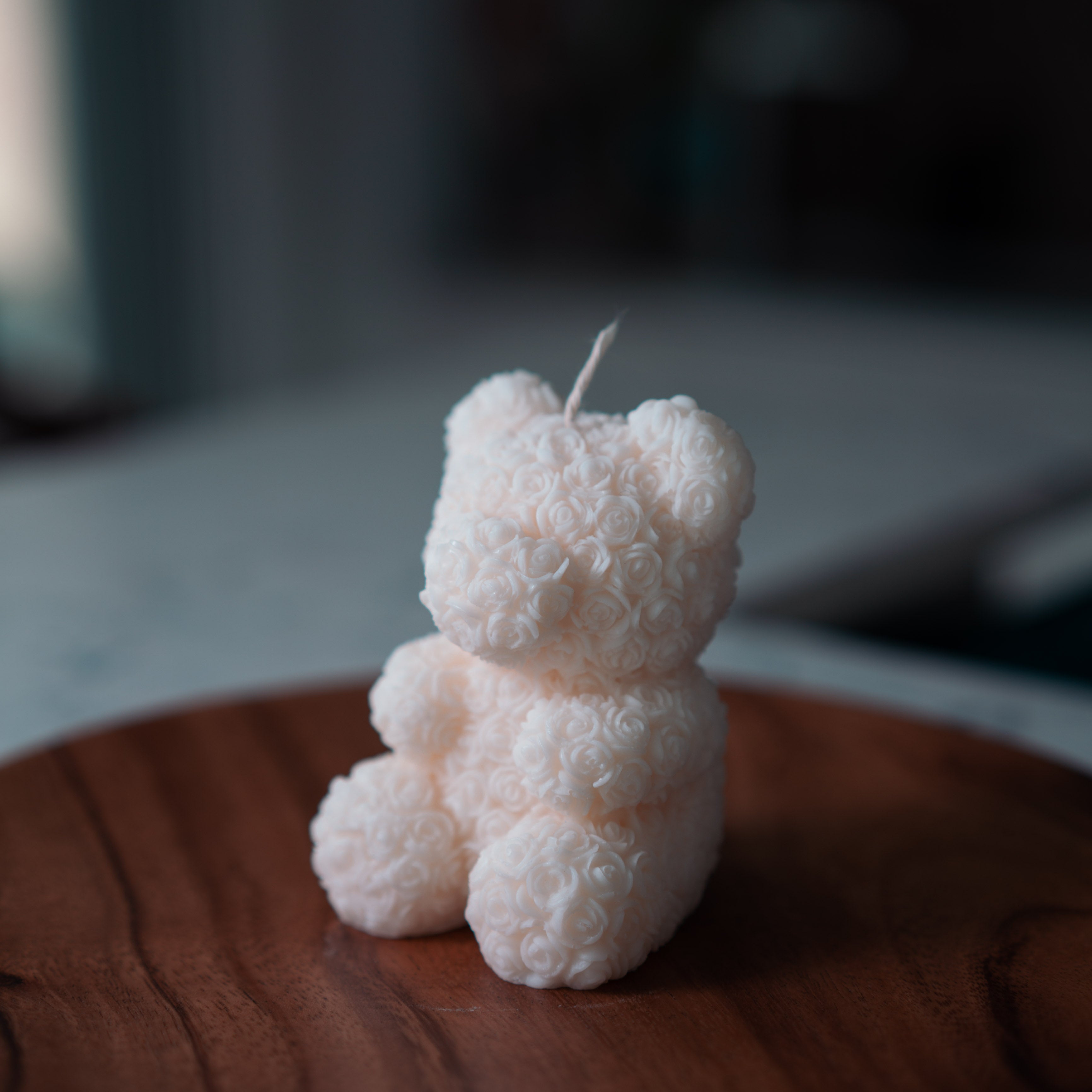 Bear Shaped Decorative Candle with intricate rose pattern placed on top of a round wooded surface.