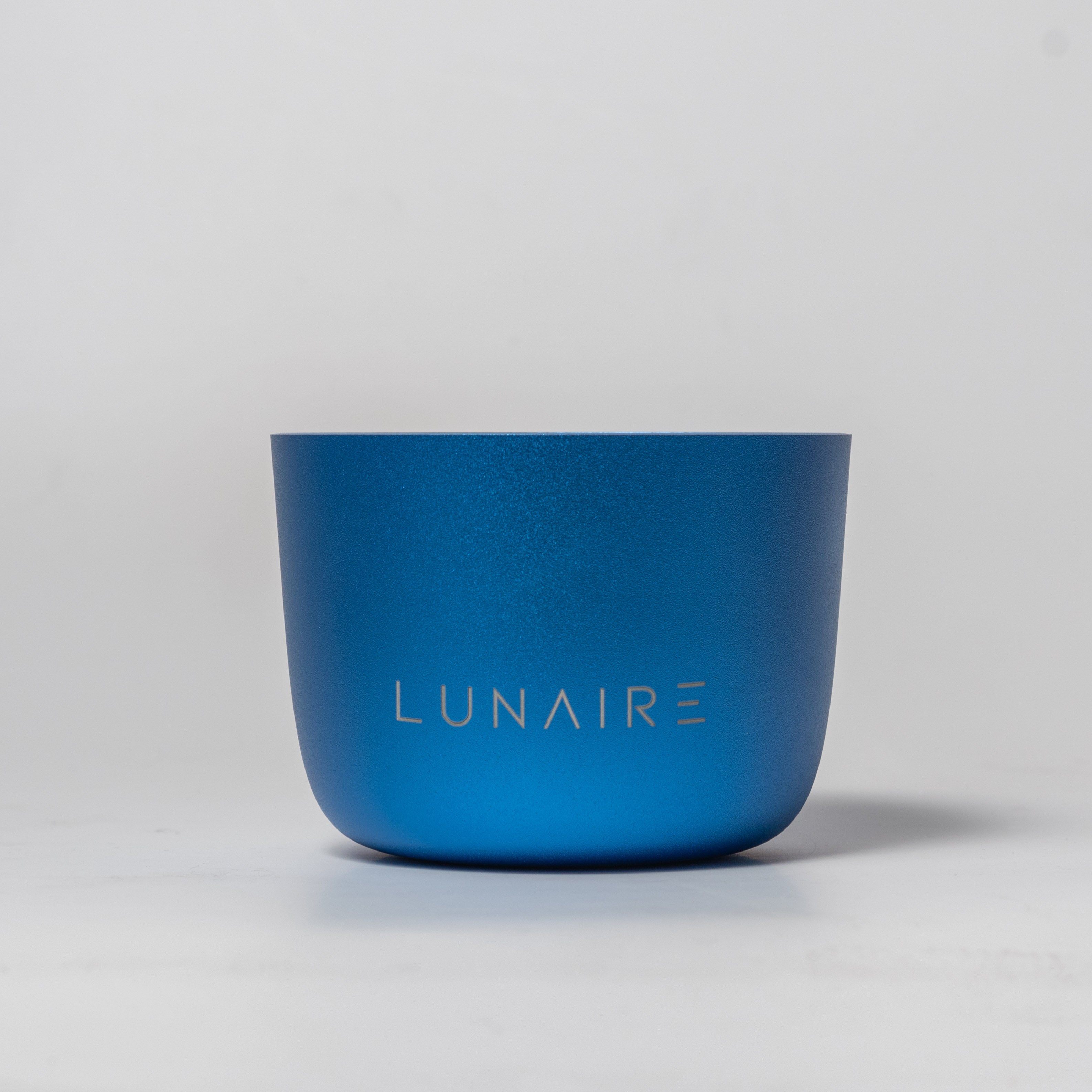 A blue aluminum candle jar with the brand name 'LUNAIRE' engraved on the front.