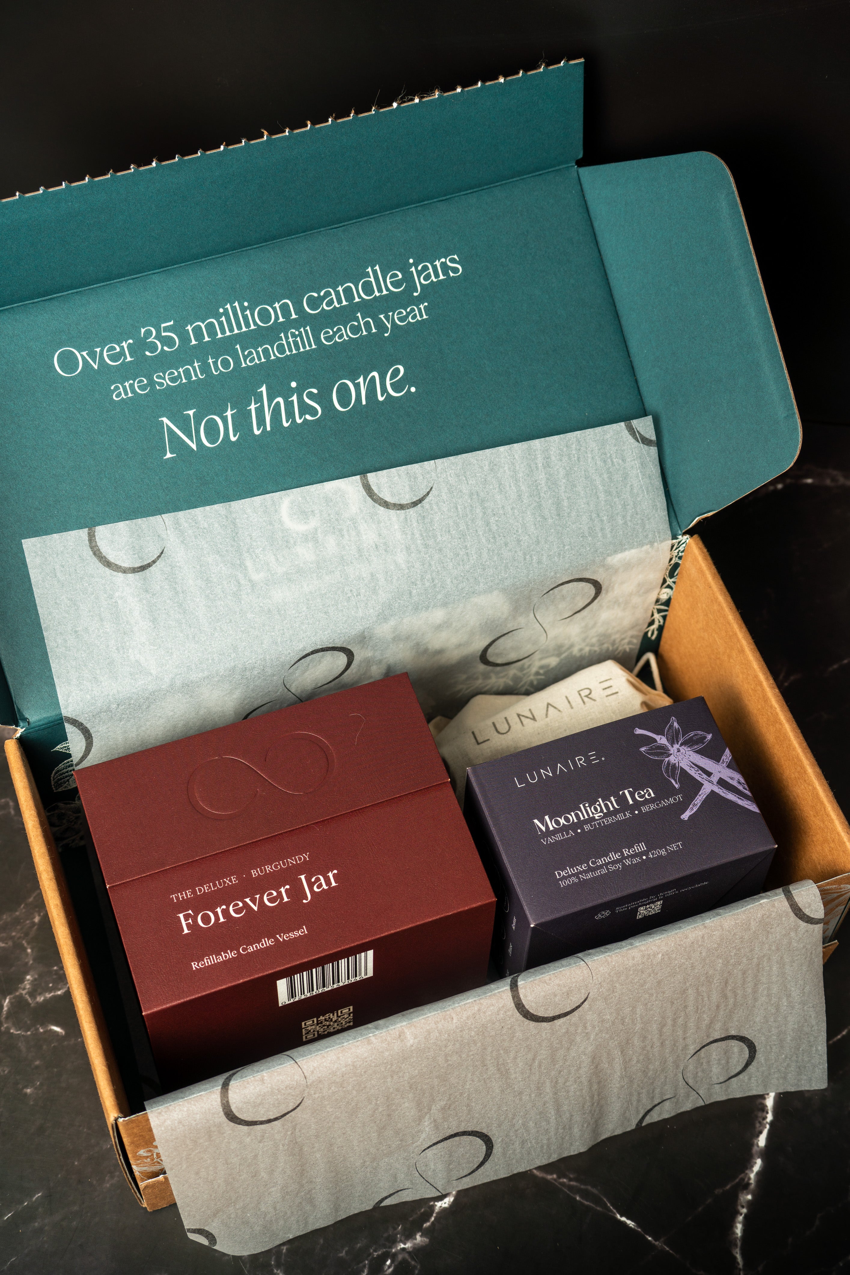 Open box containing candles with a visible message about environmental impact.