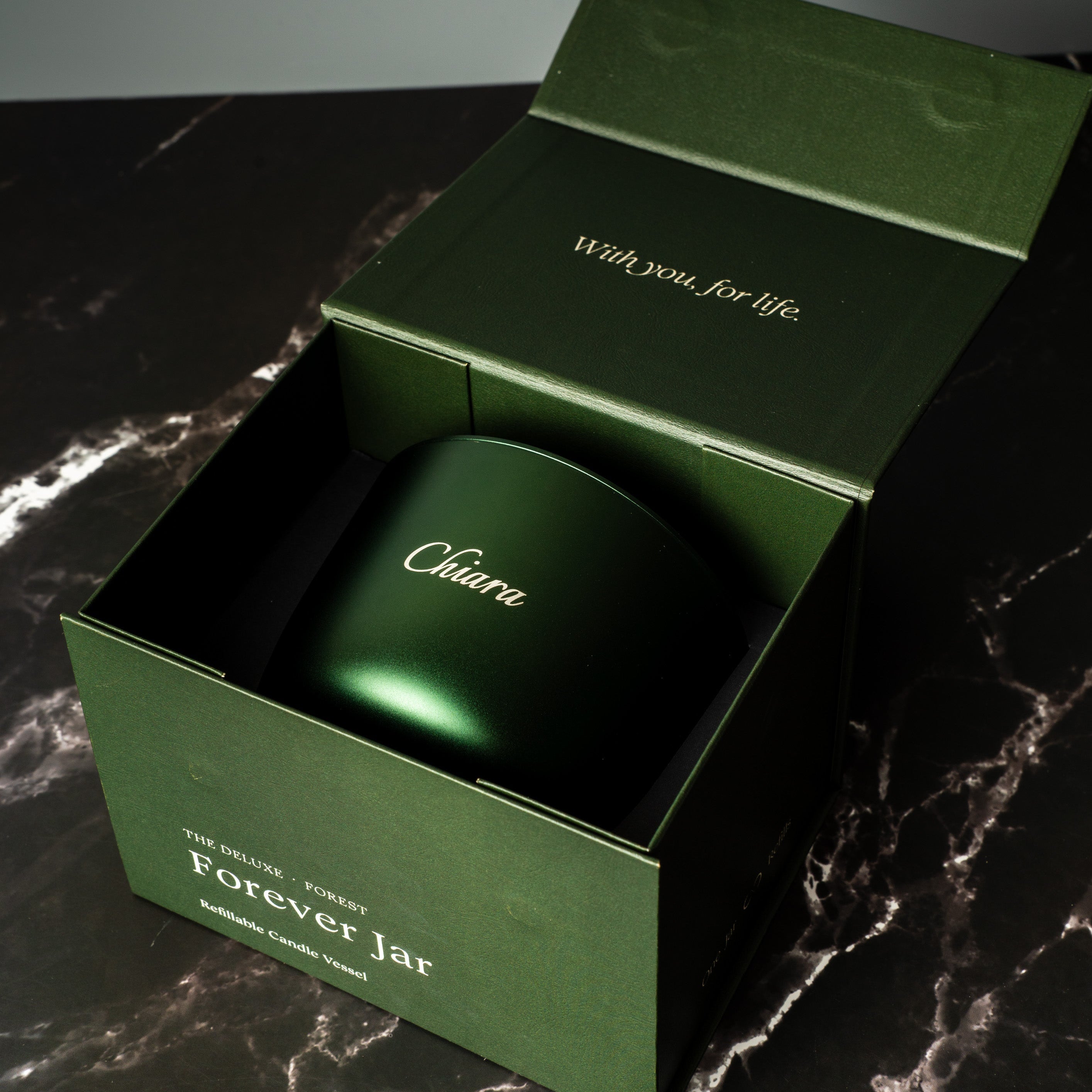 Green aluminium refillable candle in a matching box on a dark surface. Luxury Gift Box.