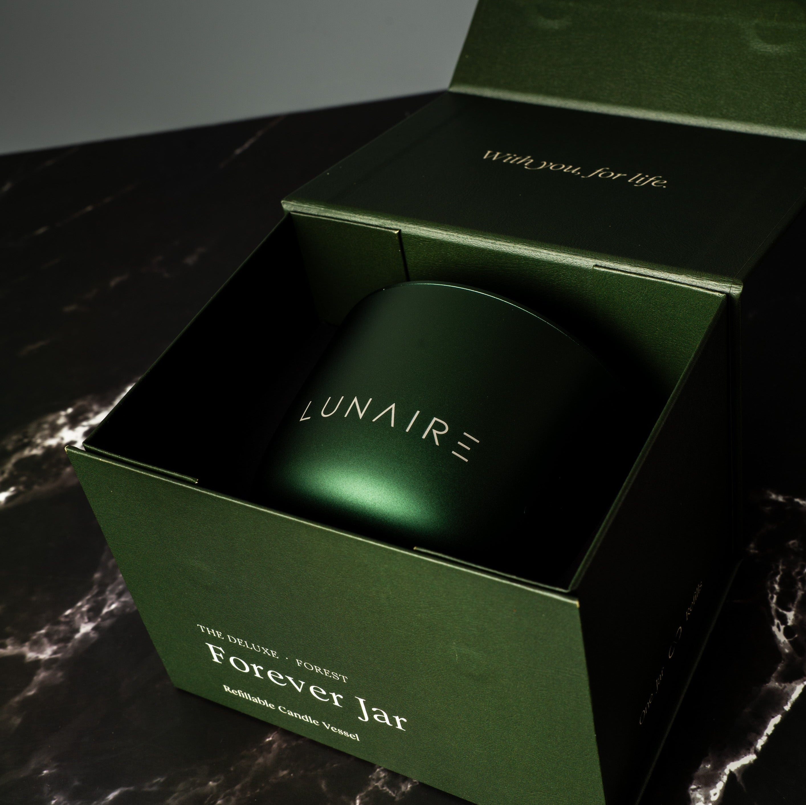Green 'LUNAIRE' refillable candle jar in a box on a dark surface