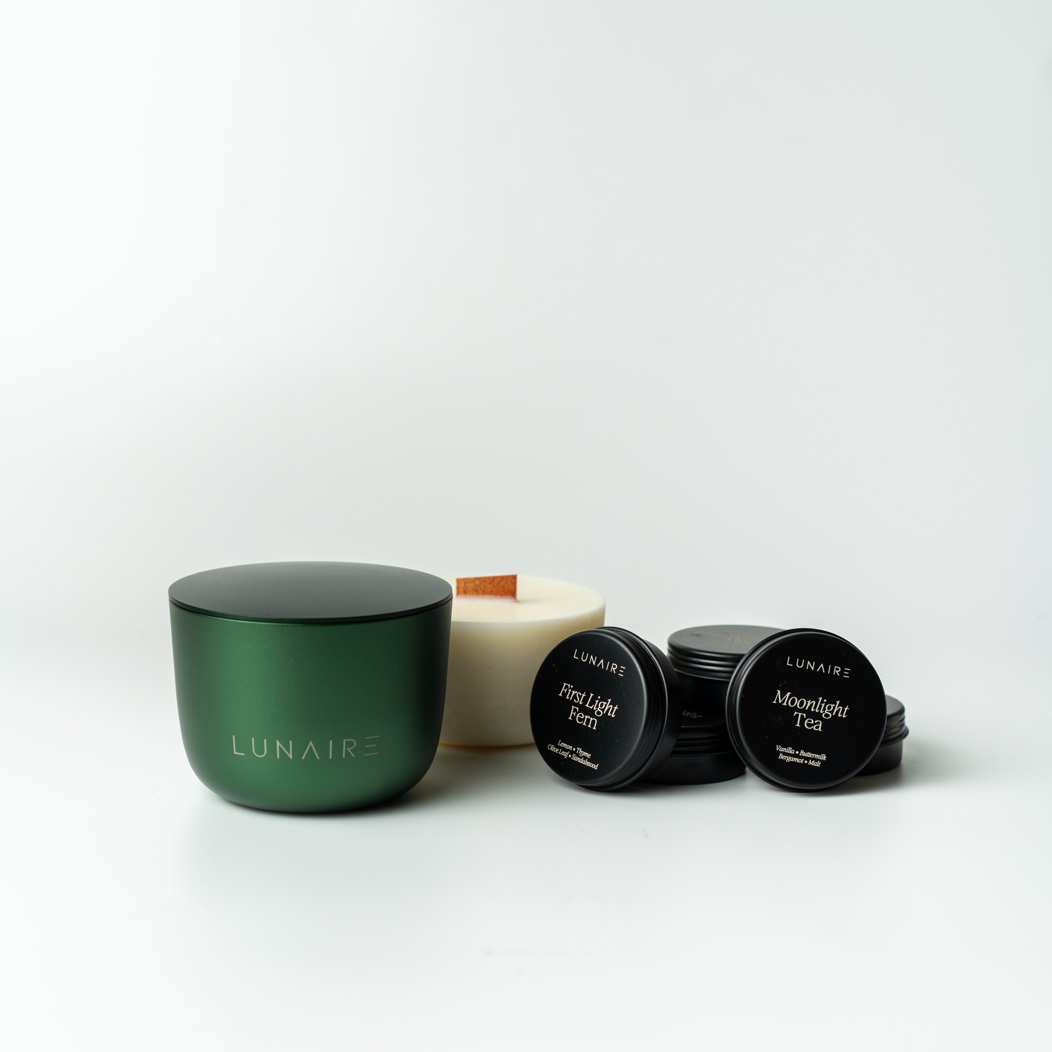 Lunaire soy vegan candle refill and tealights next to a forest green forever jar