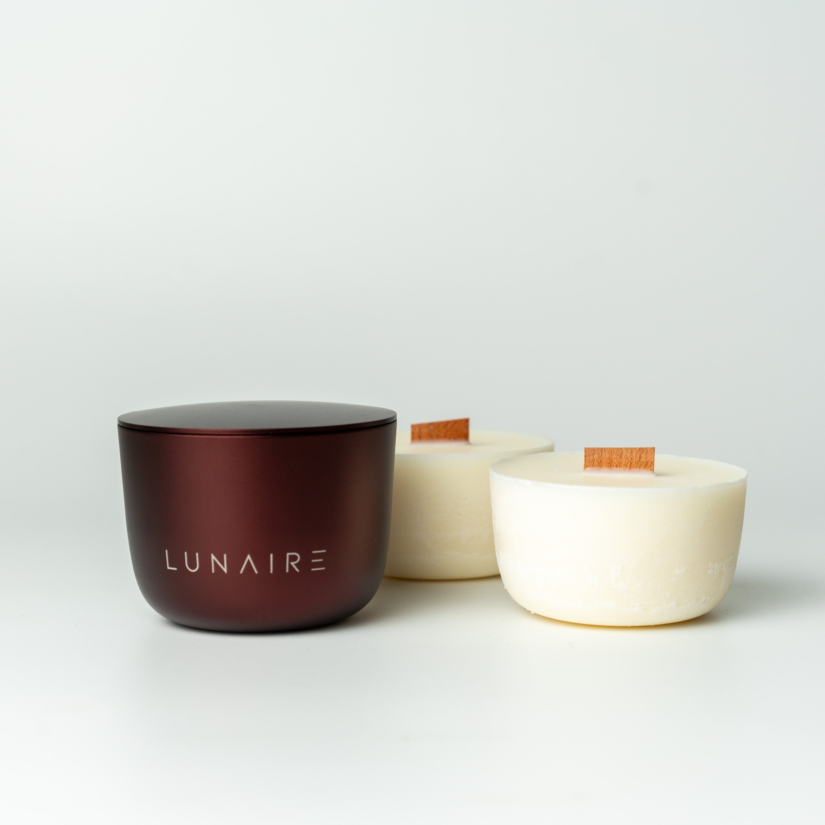 two soy candles and burgundy aluminium candle jar with 'LUNAIRE' branding on a white background