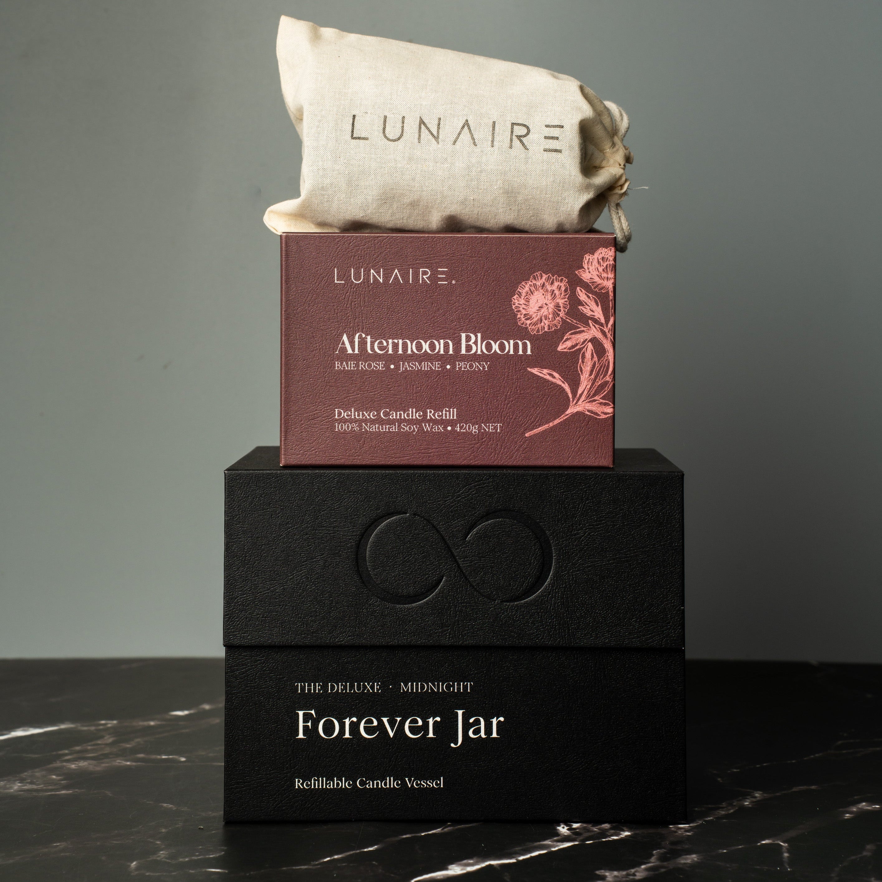 LUNAIRE soy candle and packaging on a dark surface with a gray background. premium gift.