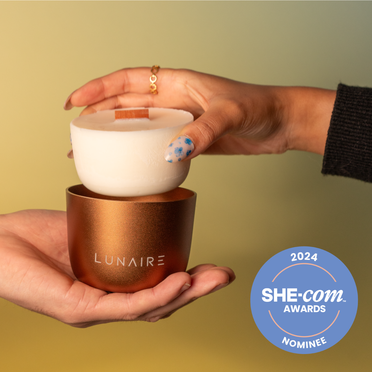 Lunaire refillable soy candles Award Nominee. Bronze forever jar held by one person and another person holding a refill.