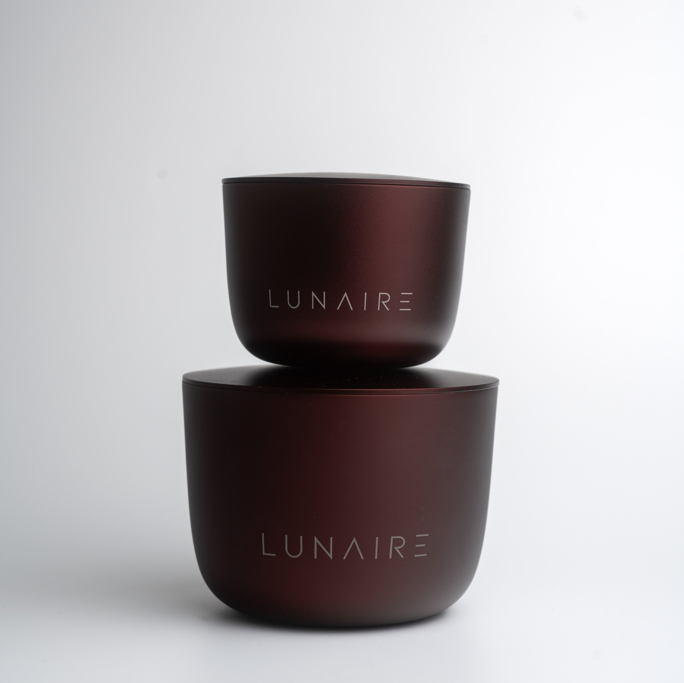 Two burgundy aluminium candle containers with 'LUNAIRE' branding on a white background