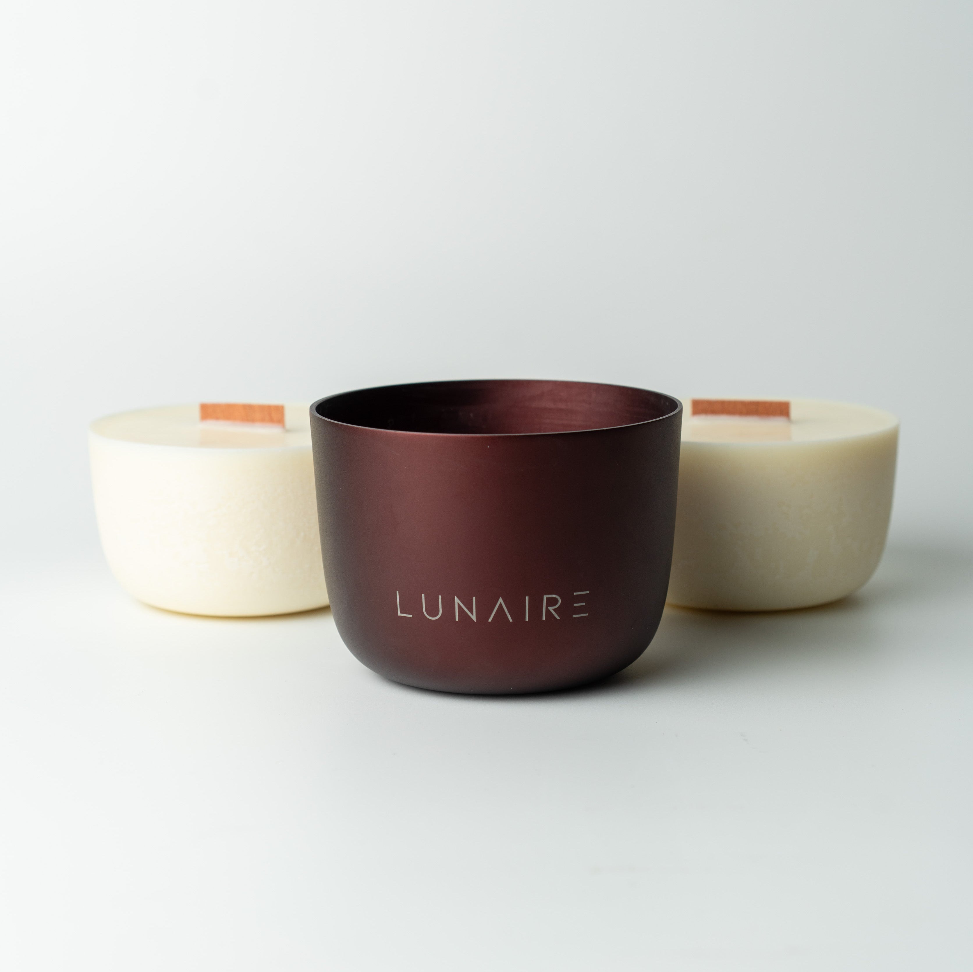 two soy candle refills and burgundy aluminium forever jar with 'LUNAIRE' branding on a light gray background