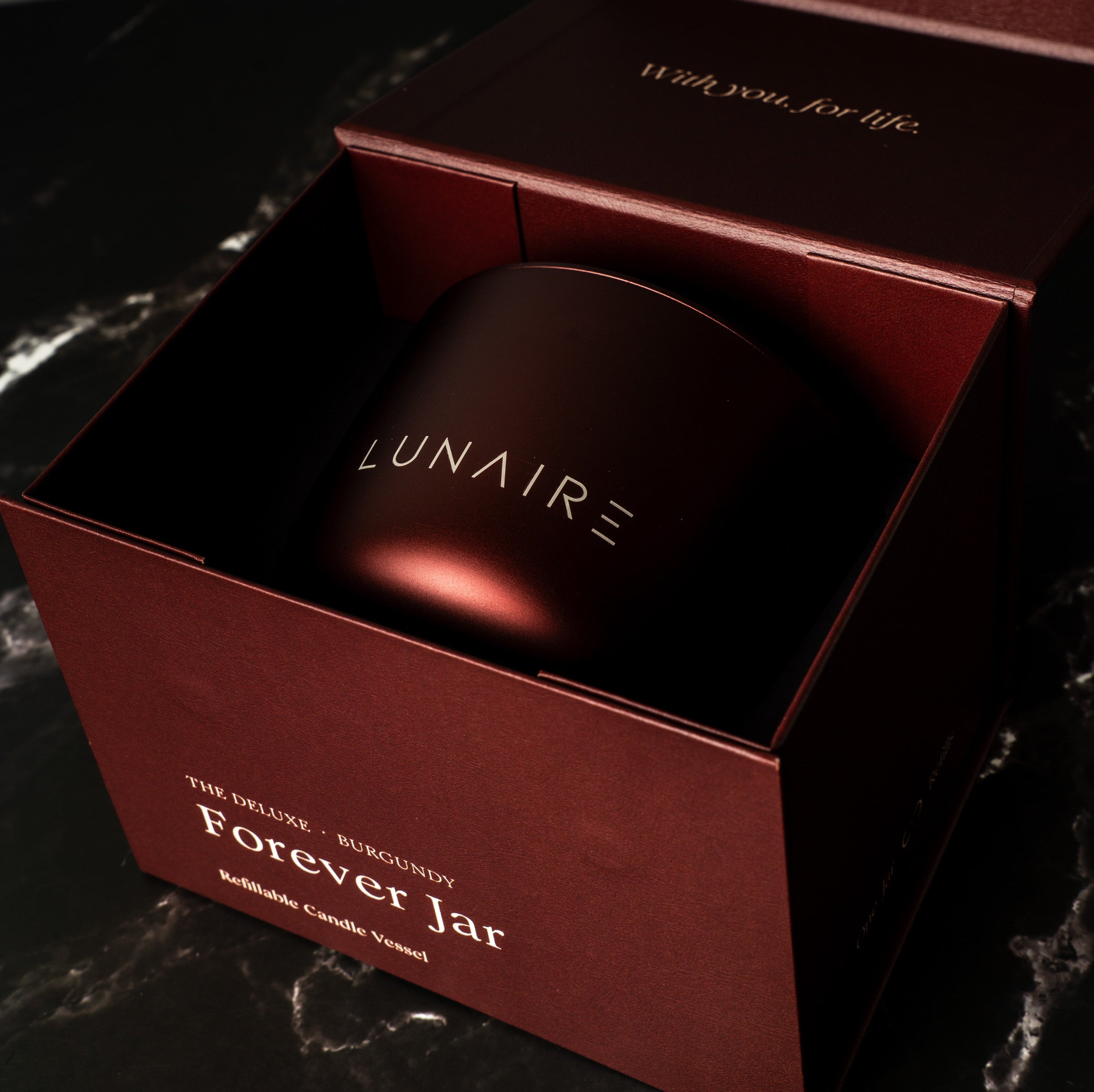Lunaire aluminium refillable candle in a red box on a dark marbled surface