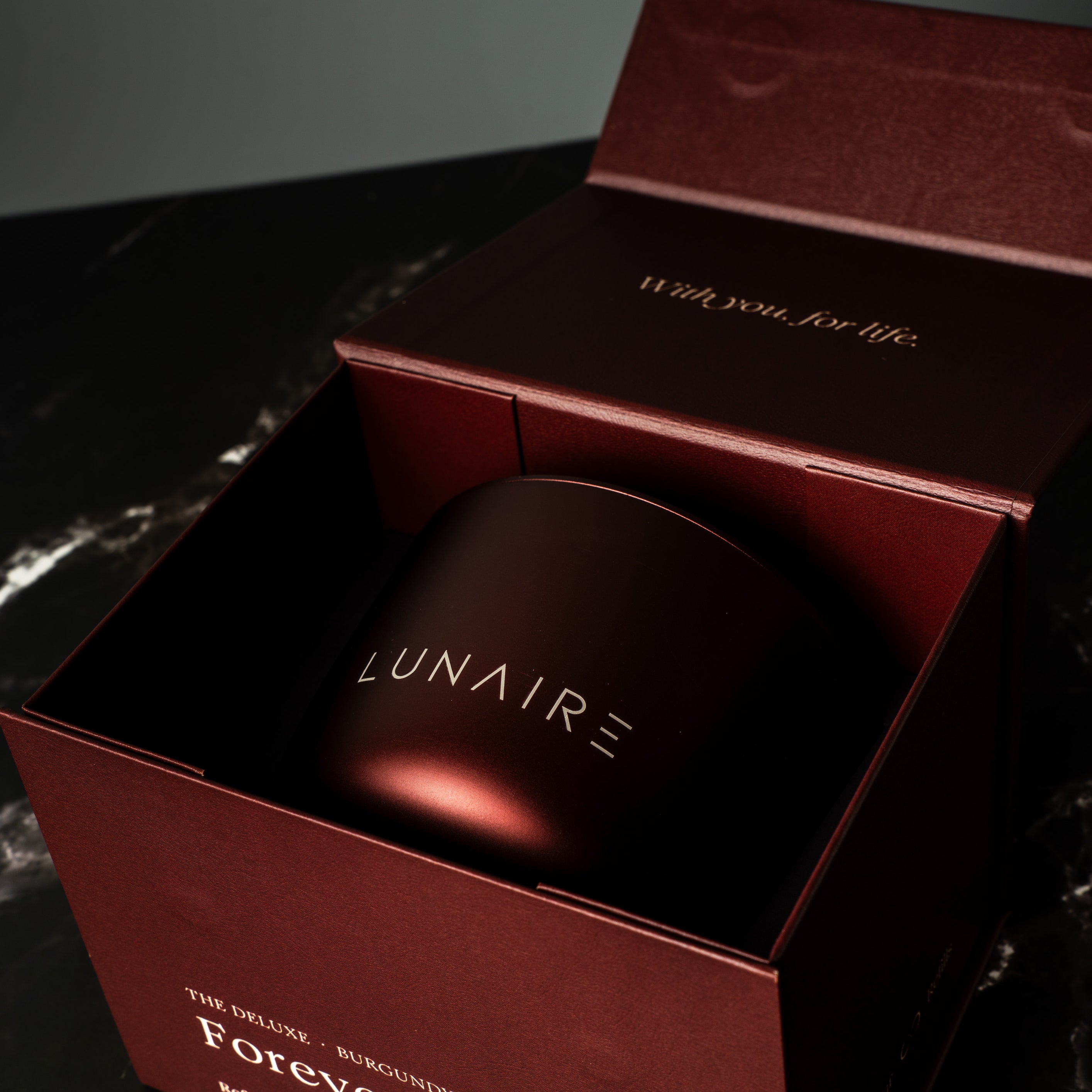 Lunaire aluminium refillable candle in a red box on a dark marbled surface