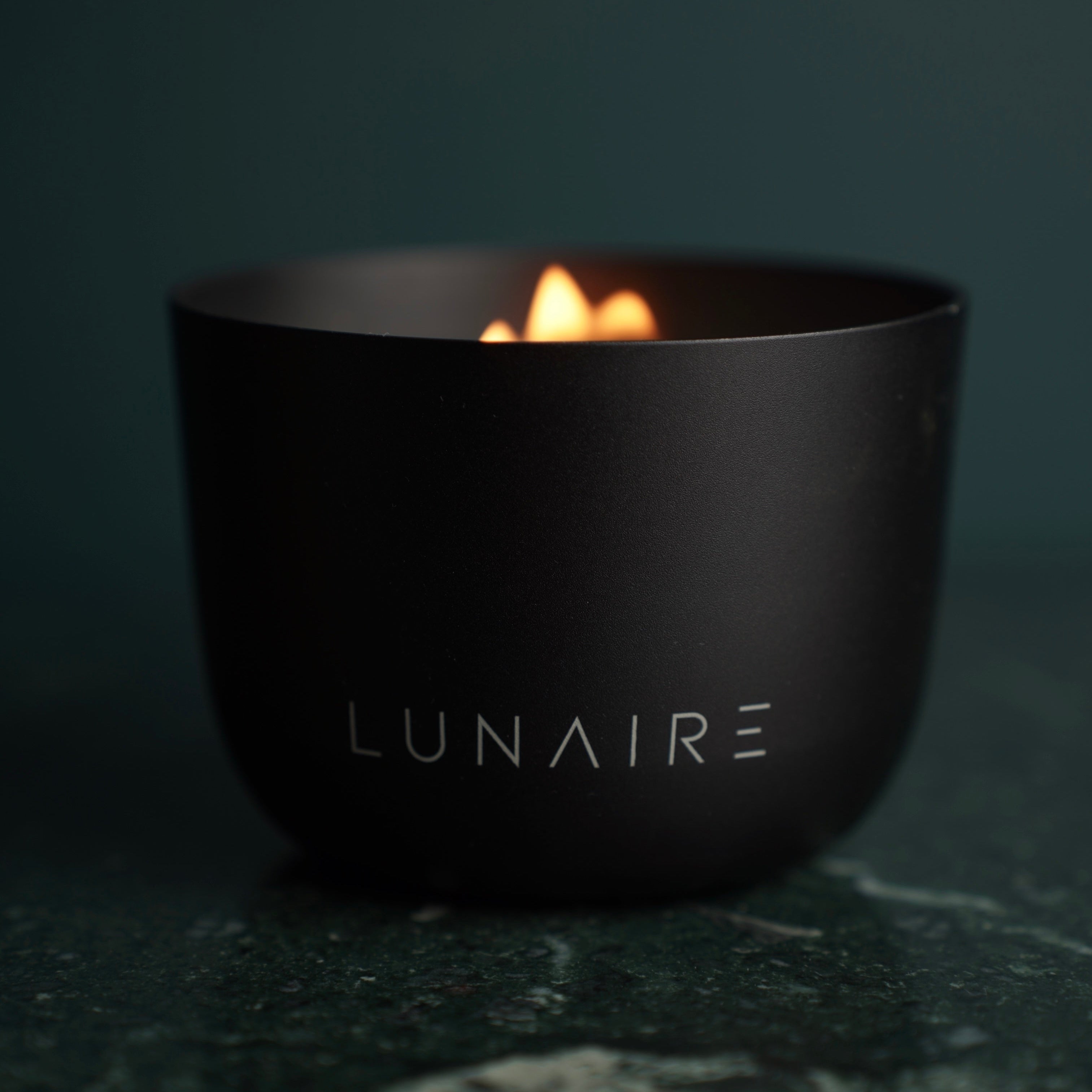 Midnight Black Aluminium candle bu Lunaire lit on a marble benchtop