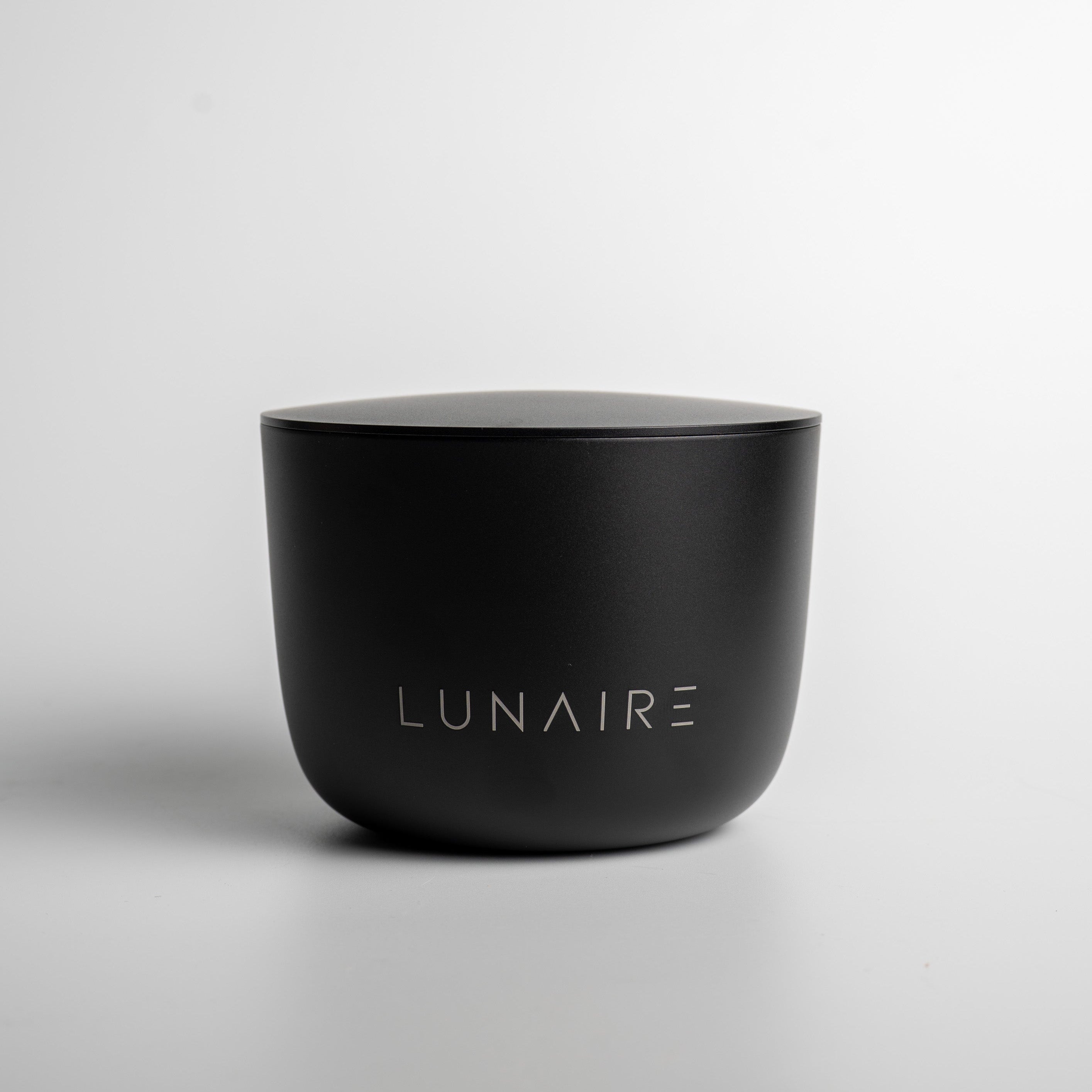 Black aluminium candle with 'LUNAIRE' branding on a light gray background