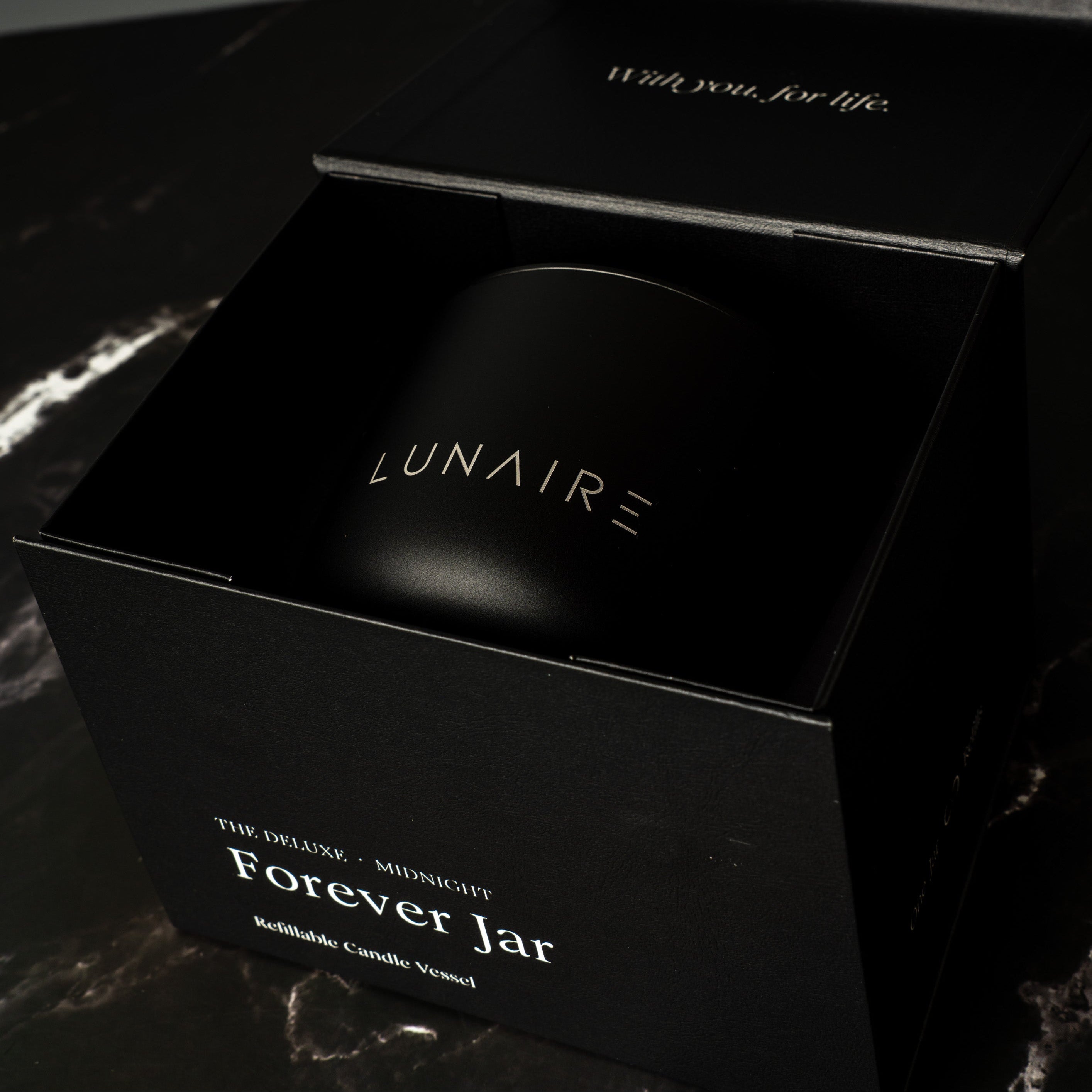 Black gift box with 'LUNAIRE' branding on a marble surface holding an aluminium candle vessel.
