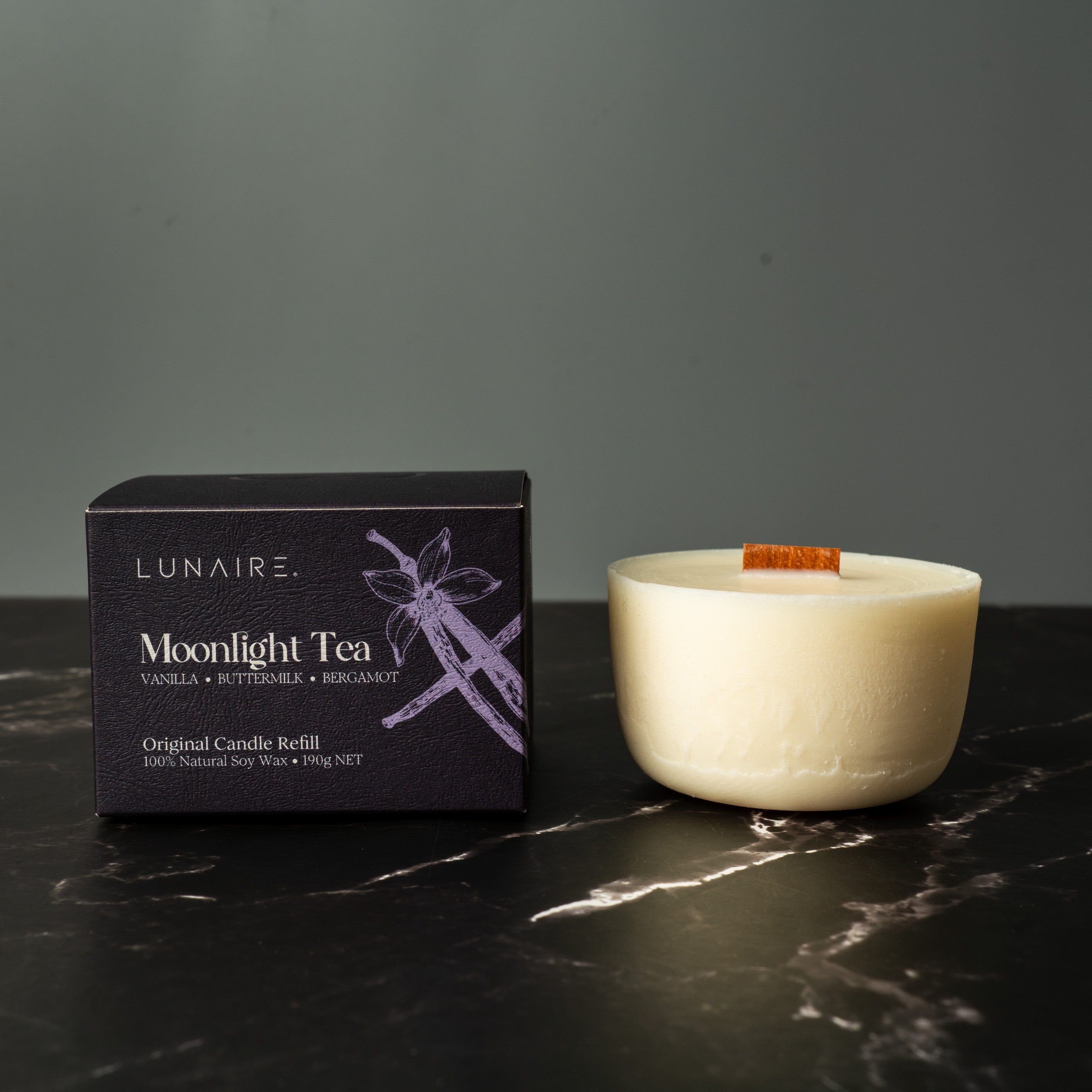 Lunaire Moonlight Tea candle refill box and candle on a dark marble surface with a gray background