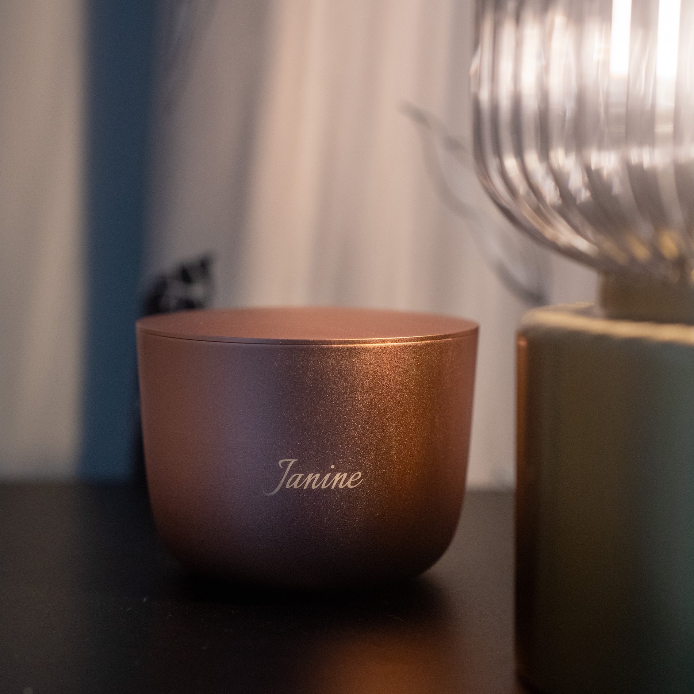 Rose Gold Aluminium Candle Vessel With engraving 'Janine' on a bedside table