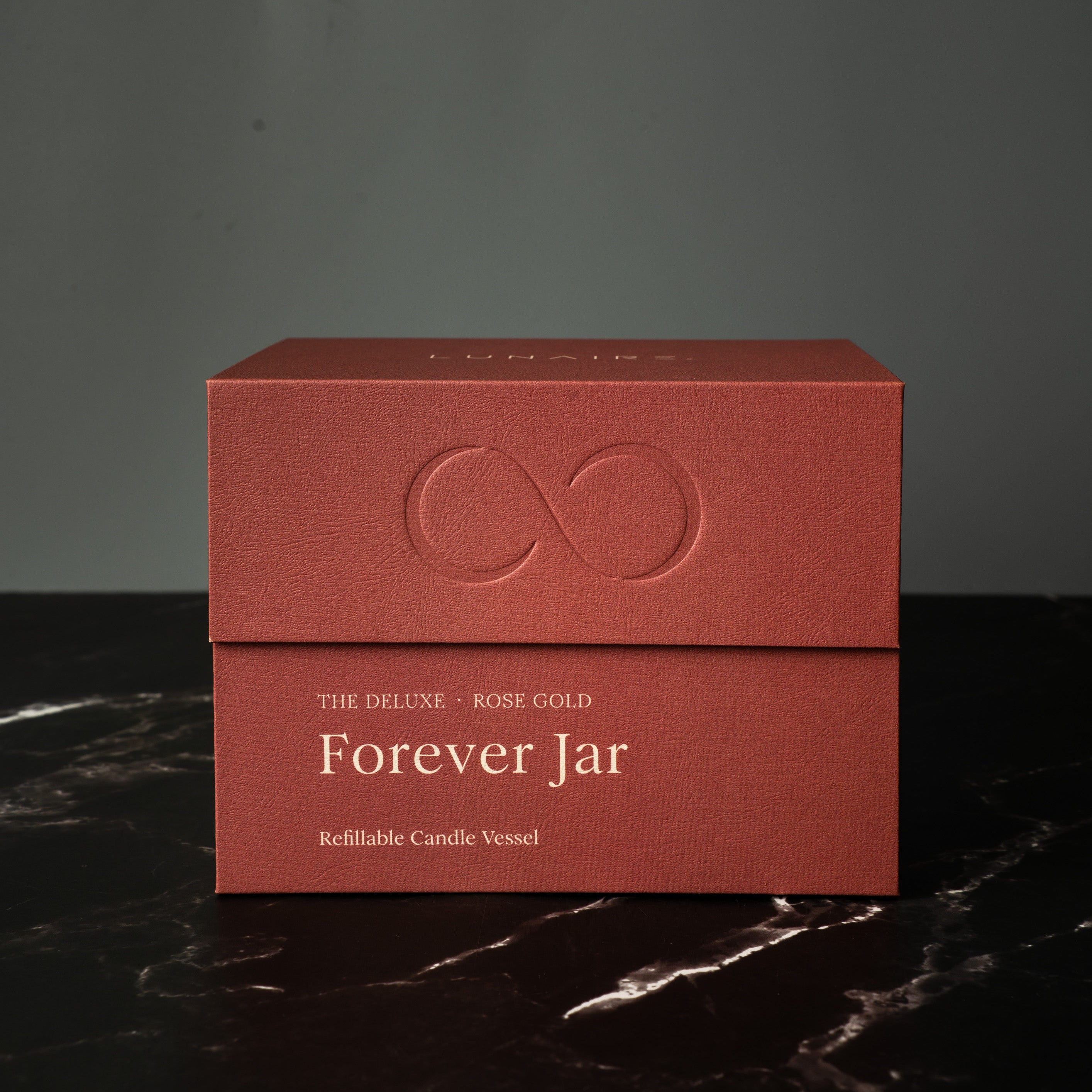 Rose Gold premium candle box labeled 'Forever Jar' on a dark surface with a gray background. Lunaire Refillable Aluminium Candles.