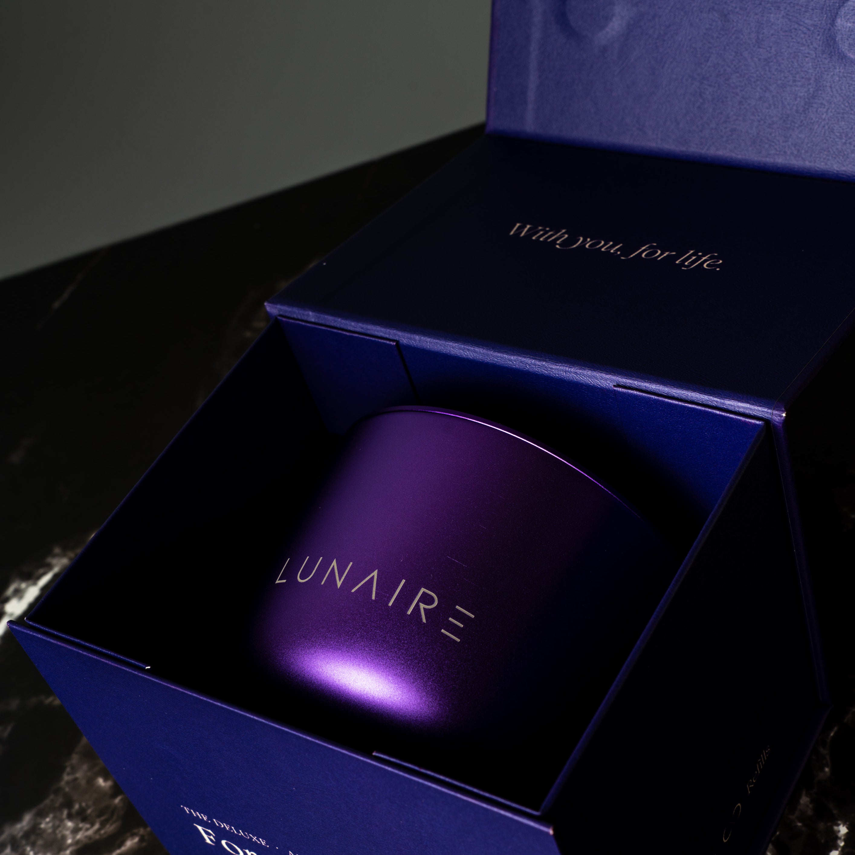 Lunaire Forever Candle  in a purple box with  branding on a dark background. refillable aluminium Candles.