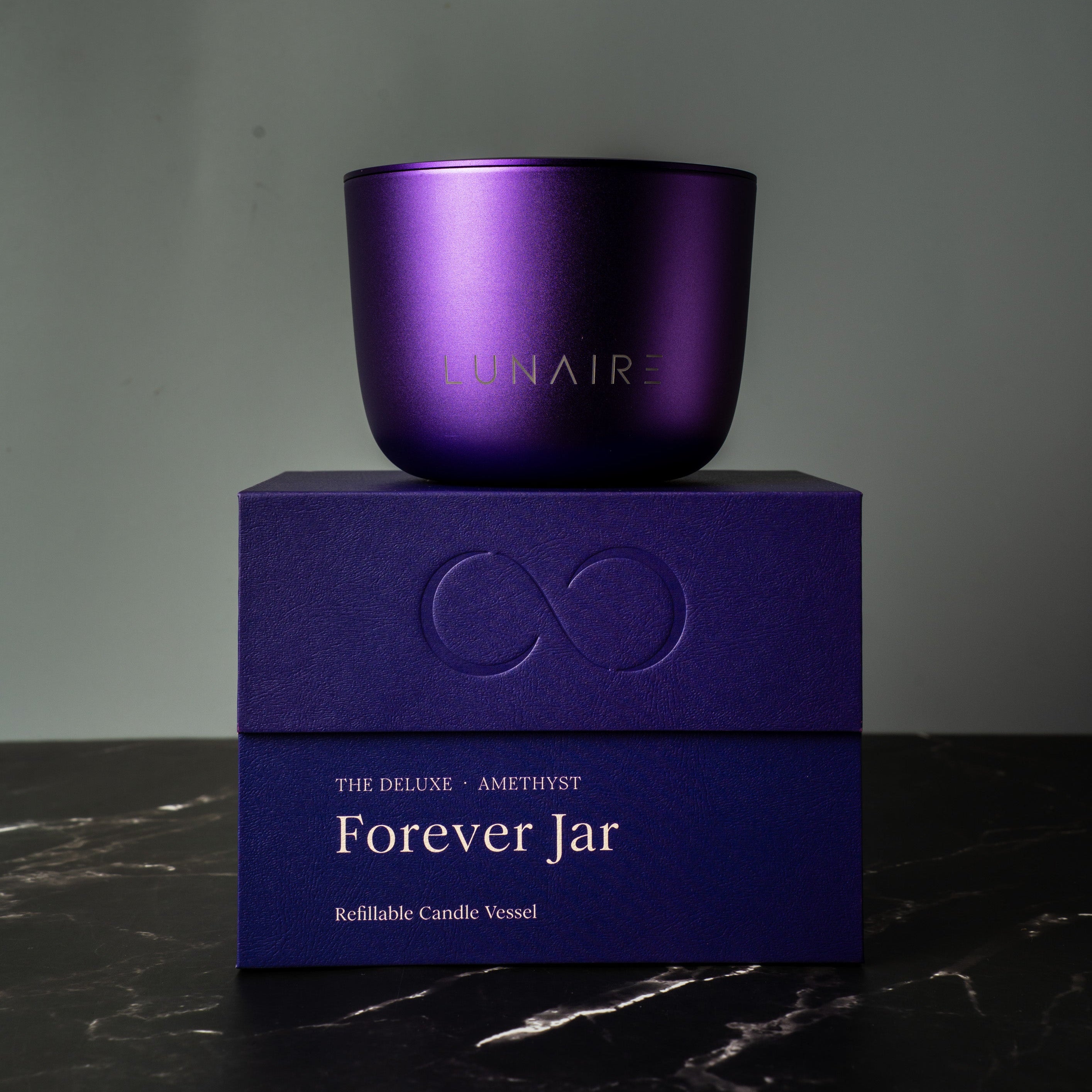 Purple refillable aluminium candle and box with 'Lunaire' branding on a dark surface.