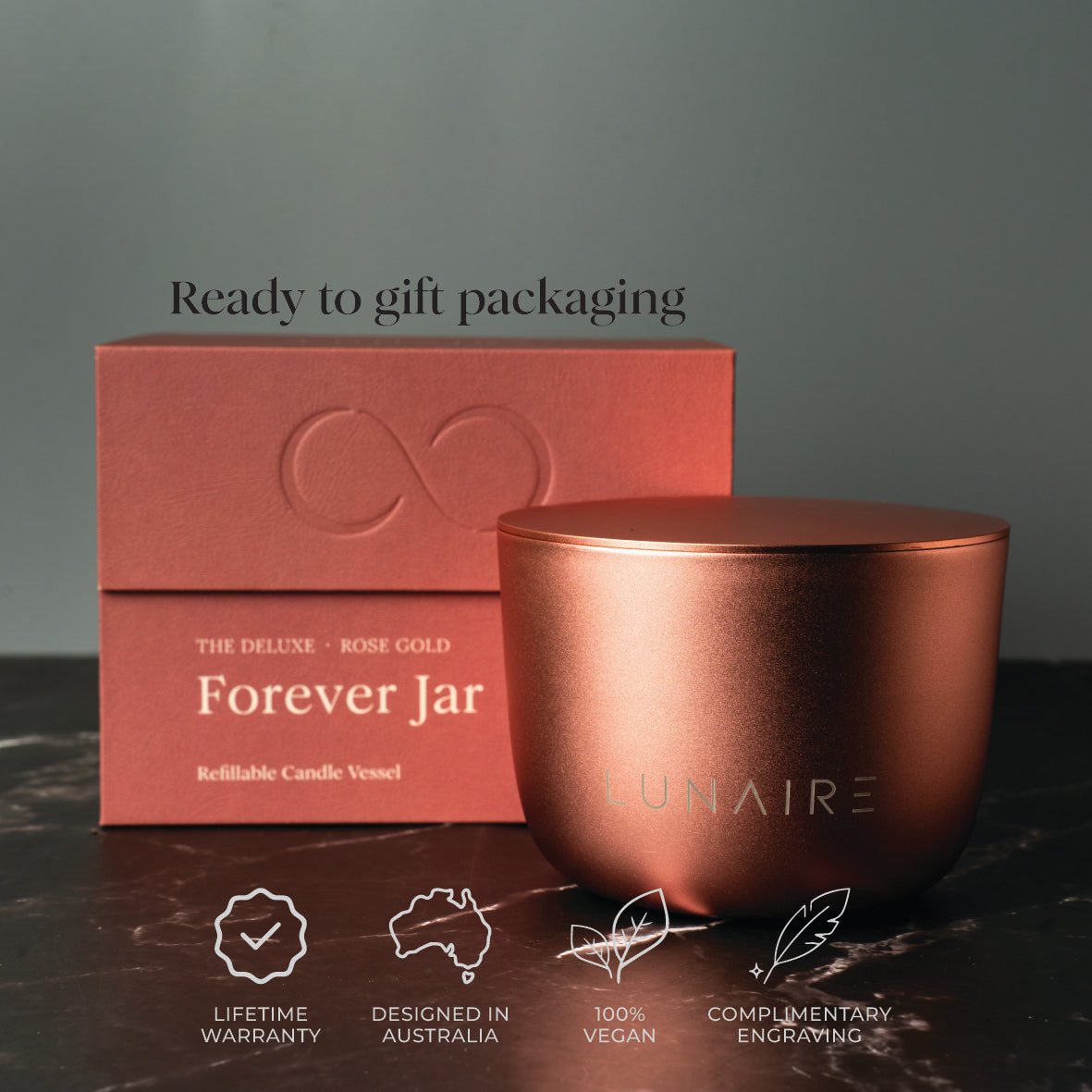 Rose gold candle vessel with packaging on a dark surface and green background