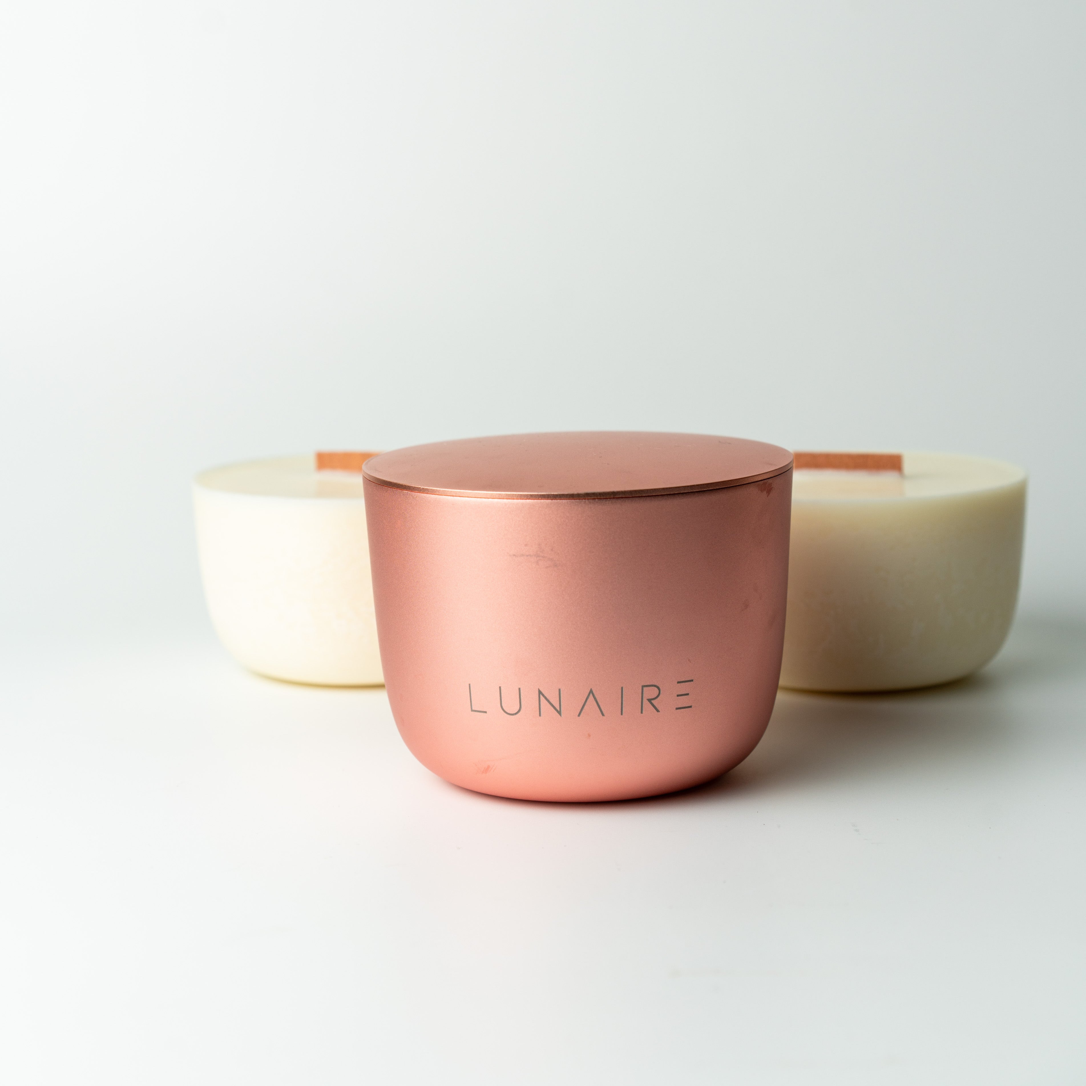 Rose gold aluminium forever candle with 'LUNAIRE' branding on a light gray background with two soy vegan refills