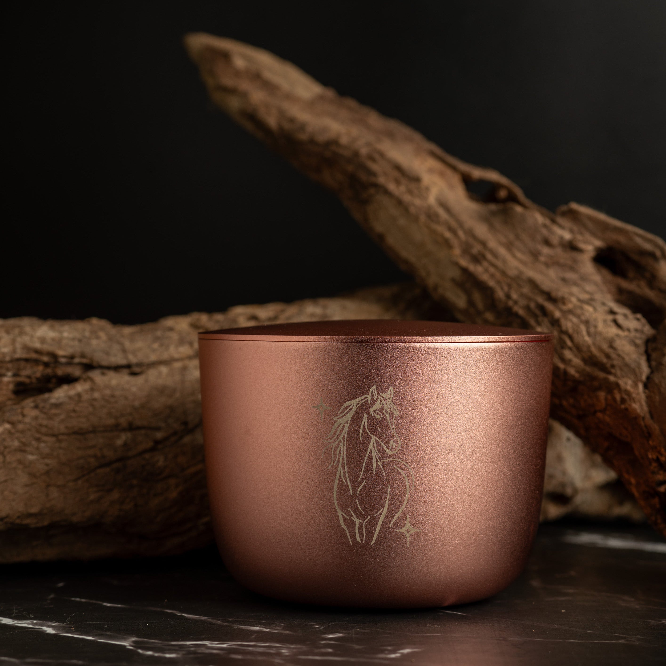 Rose gold cup with horse engraving on a dark surface with wooden elements