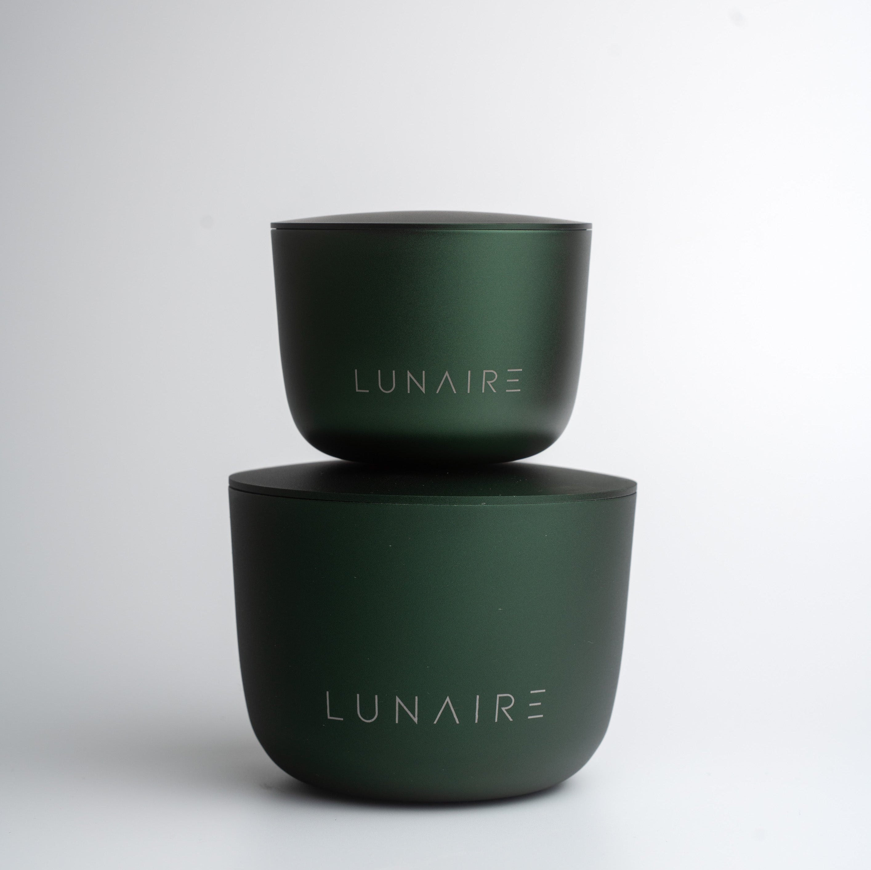 Two green aluminium candle jars with 'LUNAIRE' branding on a white background