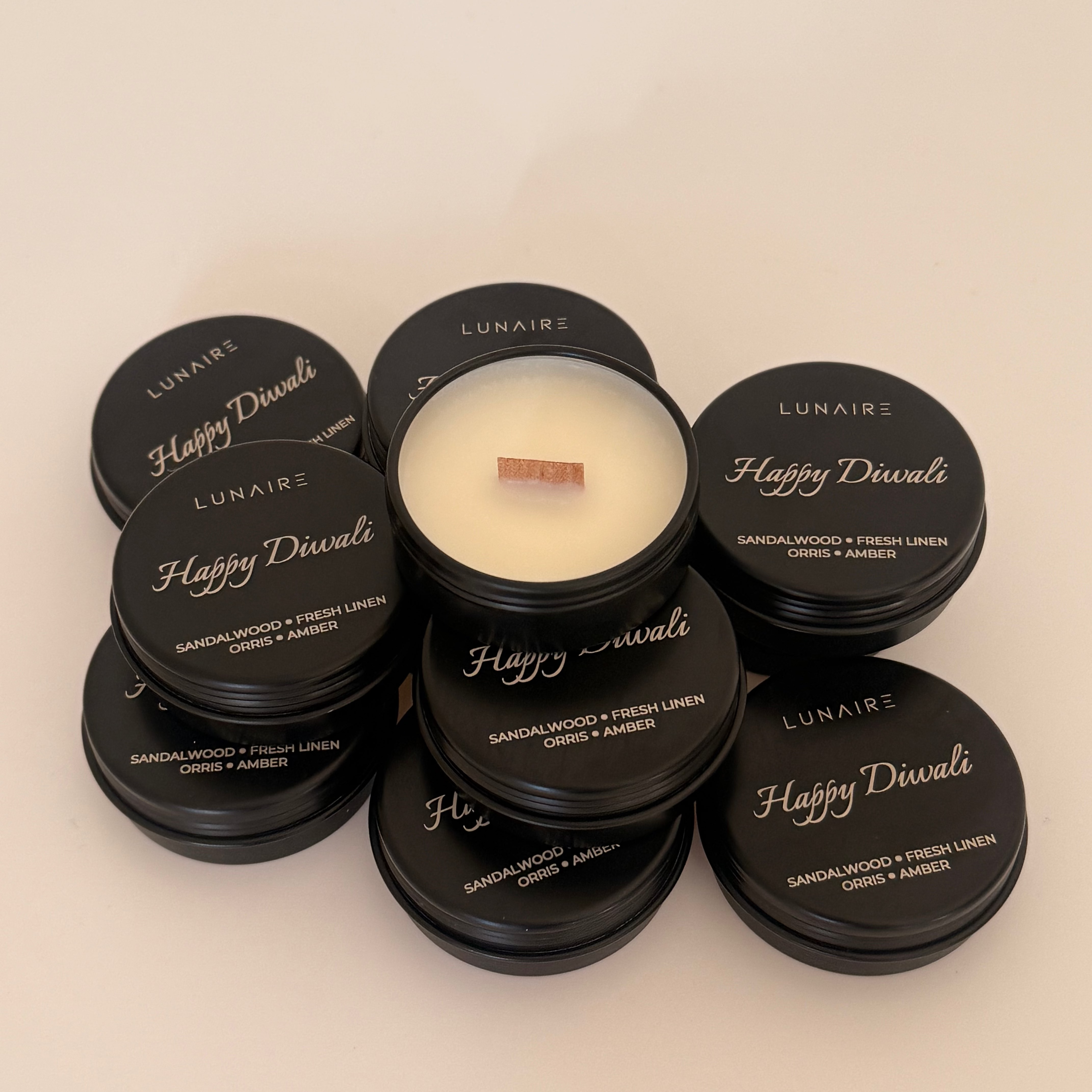 Candle with black lids labeled 'Happy Diwali' and 'Lunaire' on a beige background