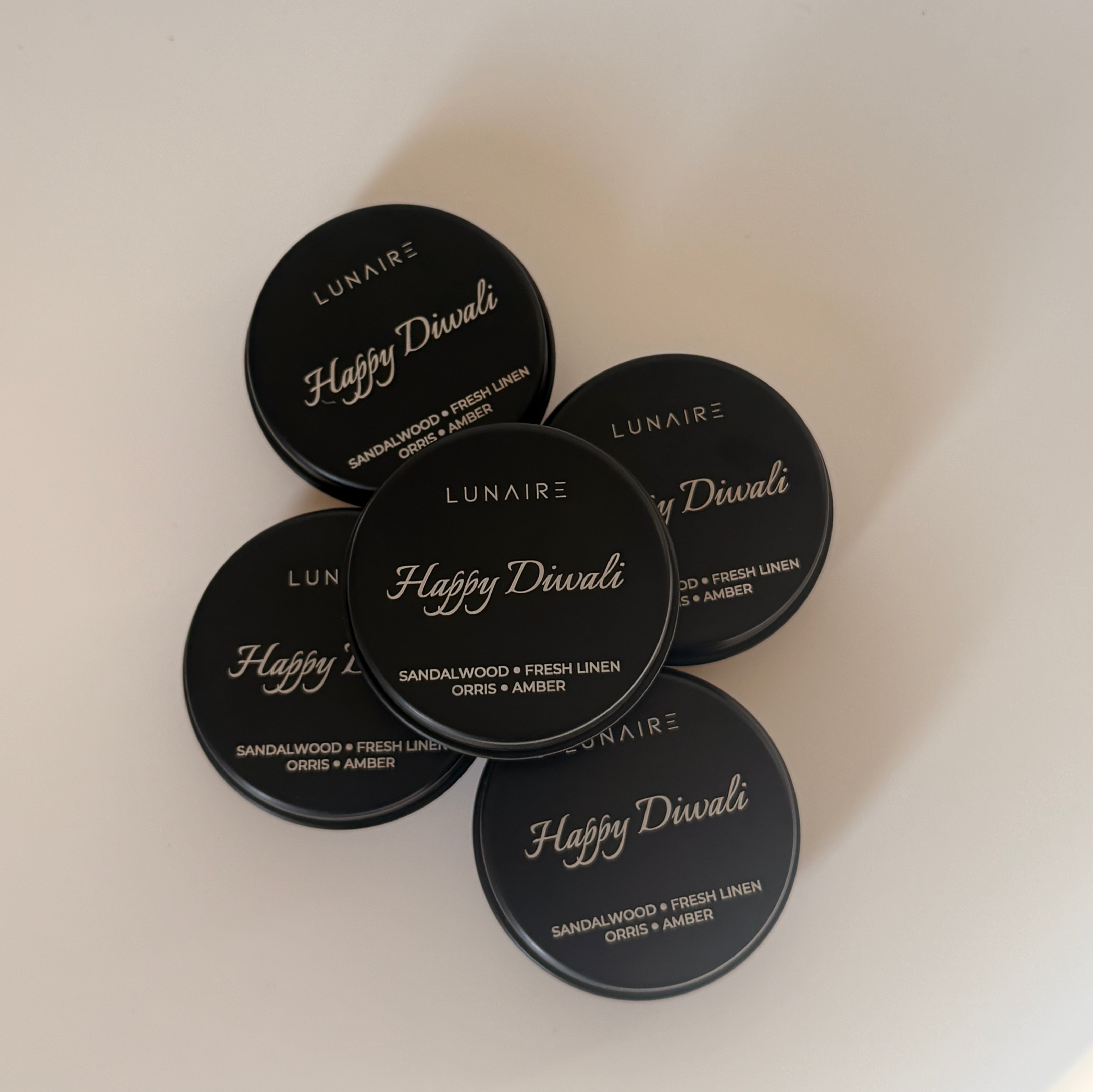 Black candles labeled 'Happy Diwali' with 'Lunaire' branding on a light background