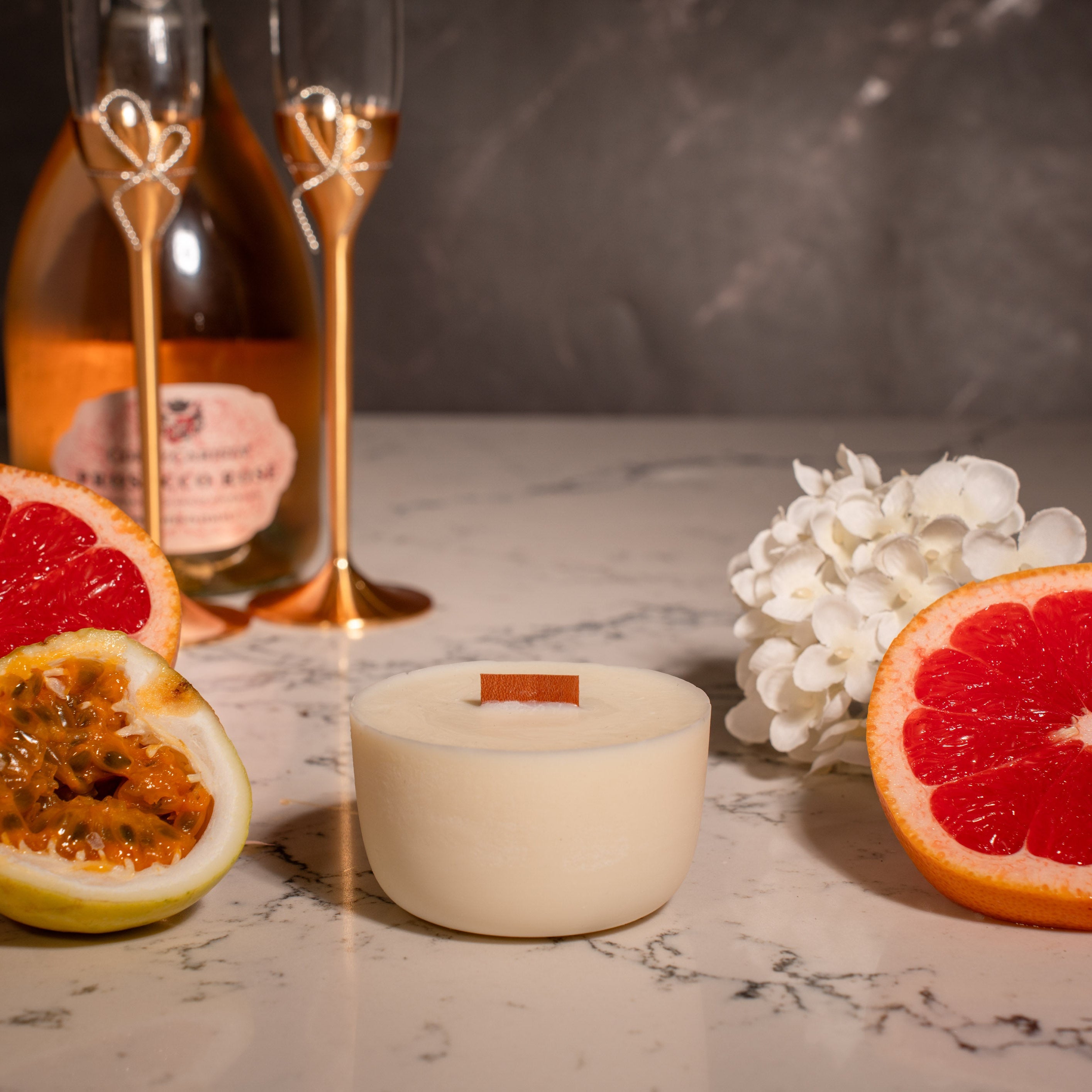 Fruit slices, a candle, and a bottle on a marble surface with a dark background