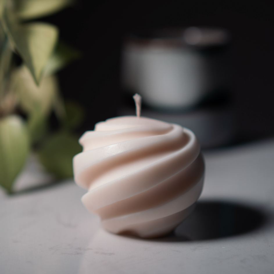 Ball Decorative Lunaire Candle with cotton wick. Plant in background.