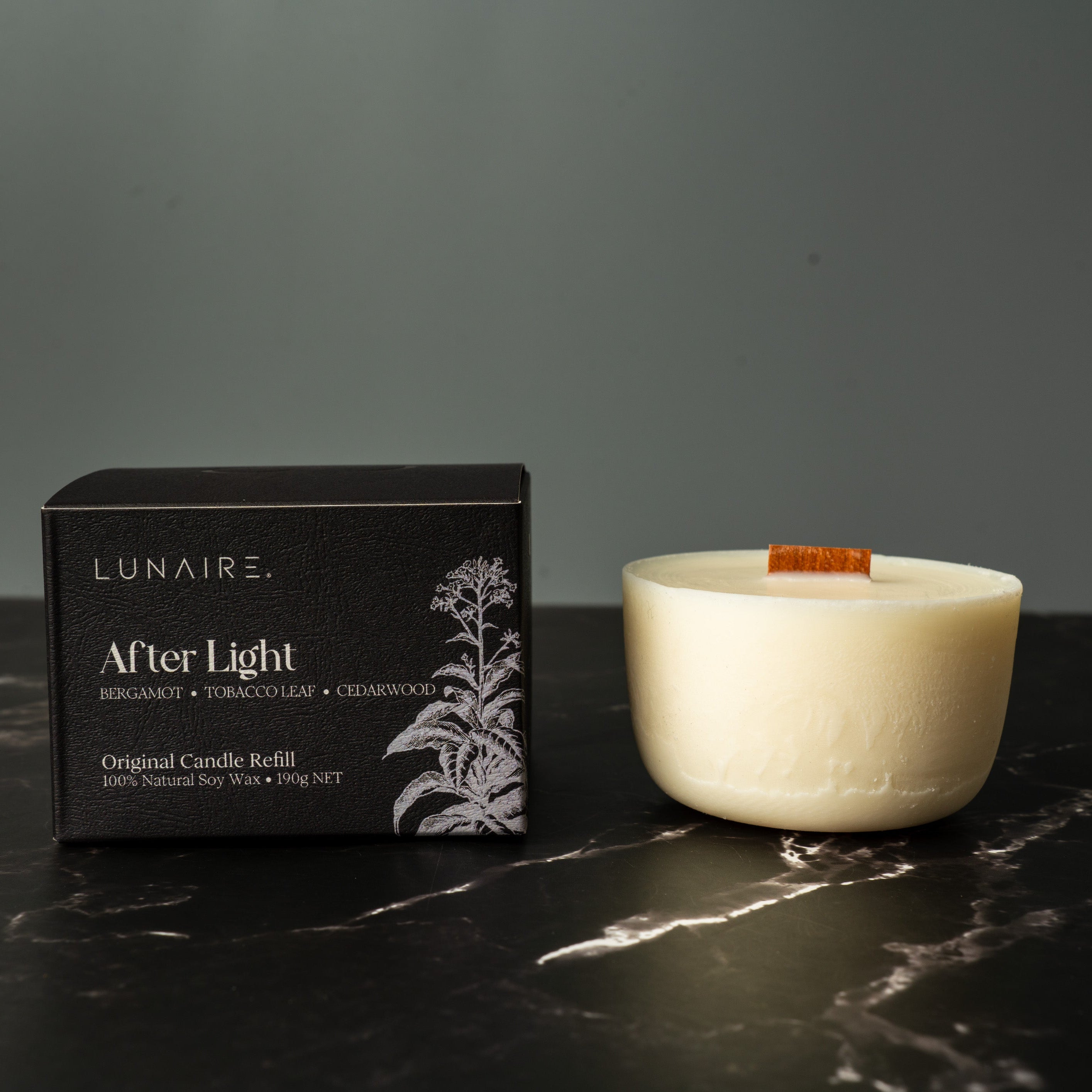 Lunaire candle refill box and candle on a dark marble surface with a gray background