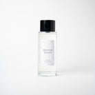 A clear glass bottle of Afternoon Bloom room mist with a black cap, centered against a clean white background.