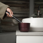 Deluxe Burgundy Forever Candle in a luxury bathroom being lit by a lunaire lighter