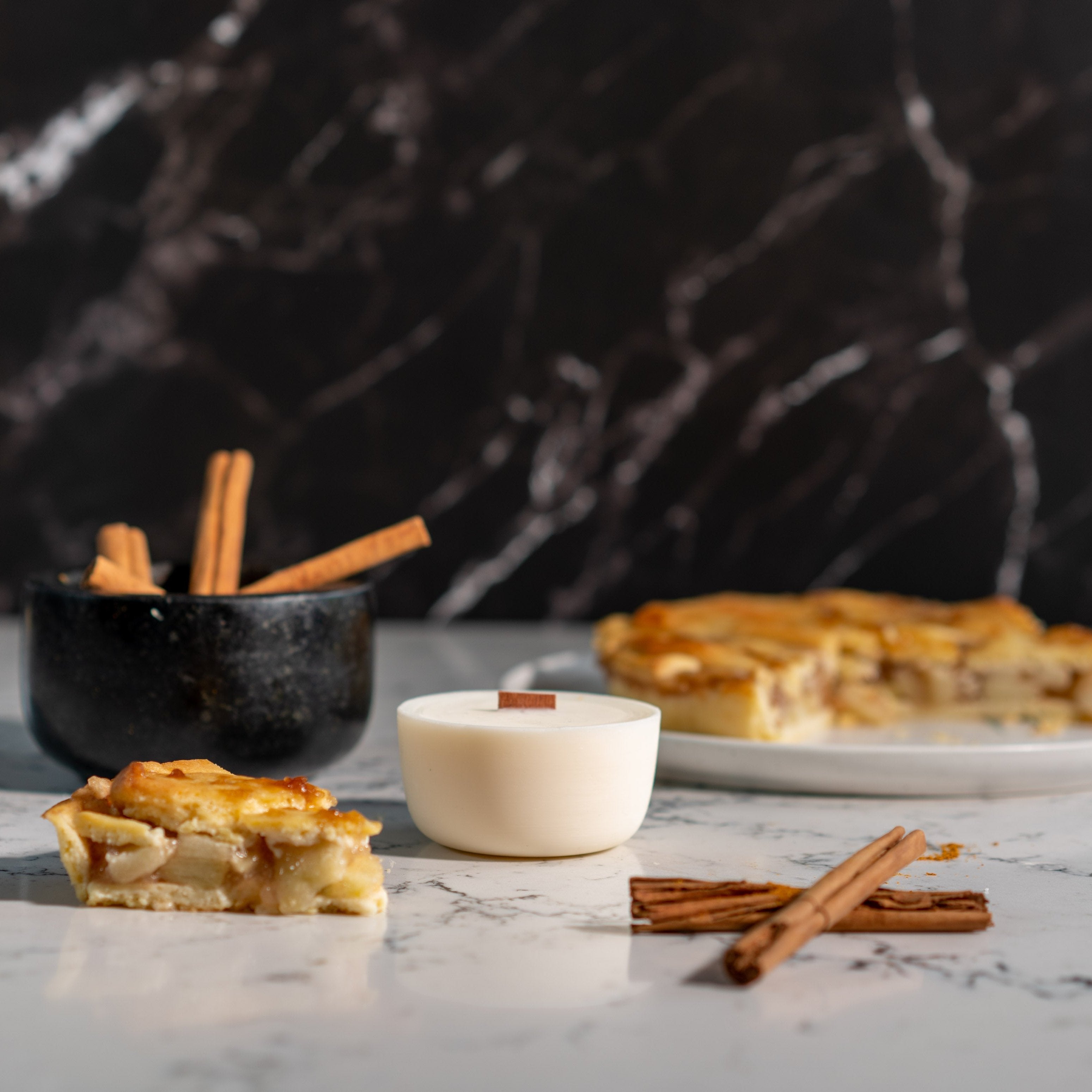 Baked Apple Pie candle Refill on a marbled bench top surrounded by a pie, cinnamon sticks and a mortar.