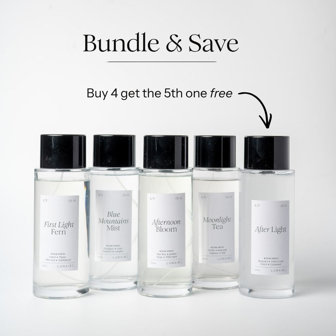 Five clear glass room spray bottles with black caps are lined up on a light gray background. Above them, text reads 'Bundle & Save' and 'Buy 4 get the 5th one free' with an arrow pointing to the rightmost bottle.