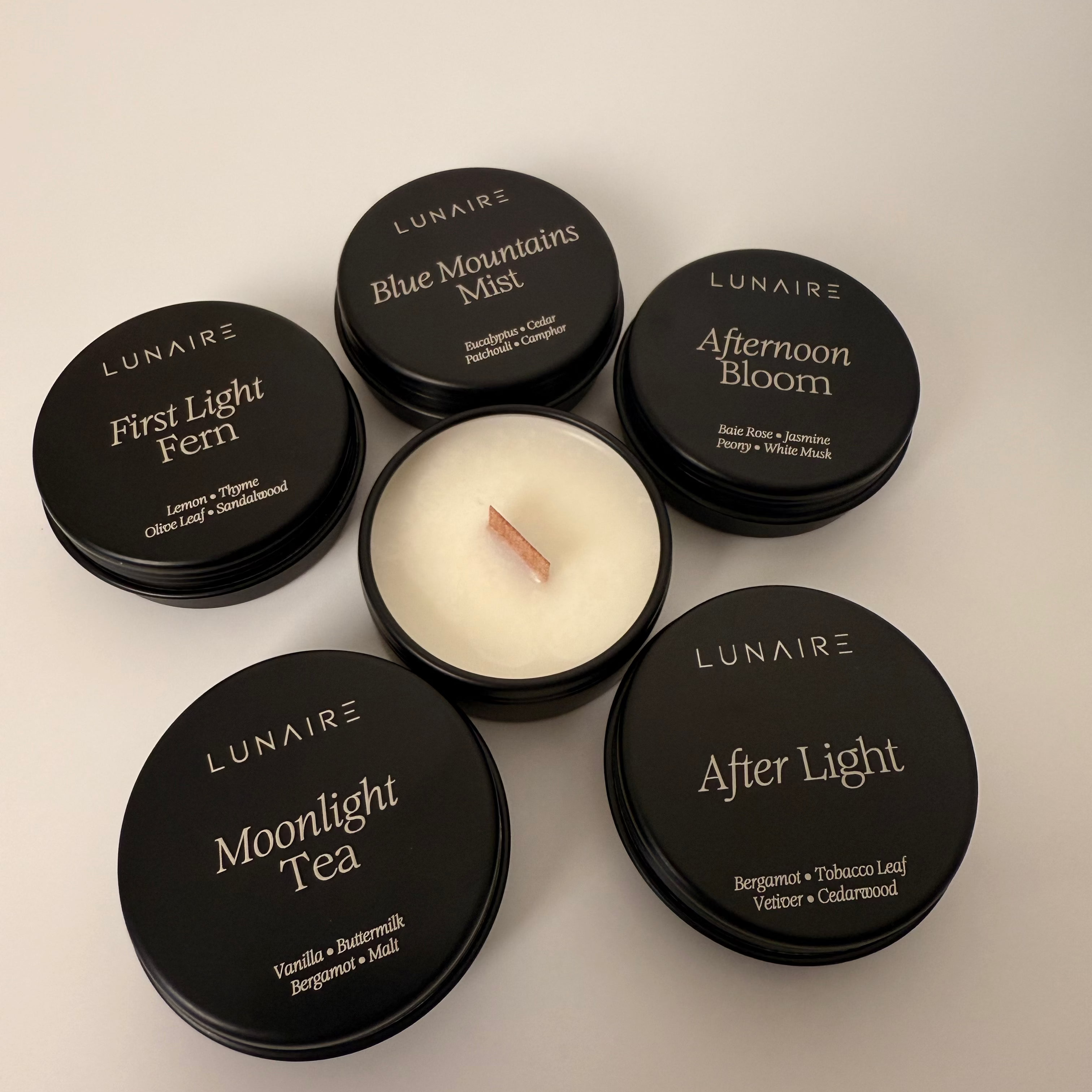 Set of Lunaire candles with black lids on a light gray background