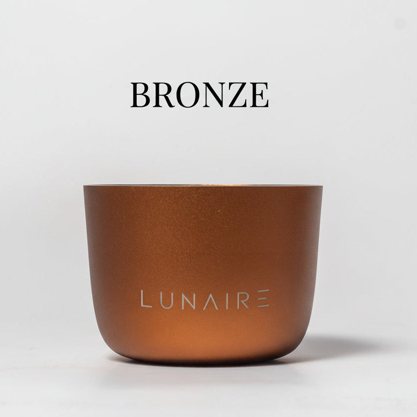 A bronze anodised aluminium candle jar with the brand name 'LUNAIRE' engraved on the front.