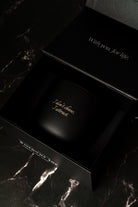 Black candle premium box with engraved text on a dark marble surface
