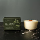Lunaire refillabl candle and packaging on a dark marble surface with a gray background