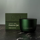 Green candle jar with 'LUNAIRE' branding and packaging on a dark surface. Luxury premium Gift. 
