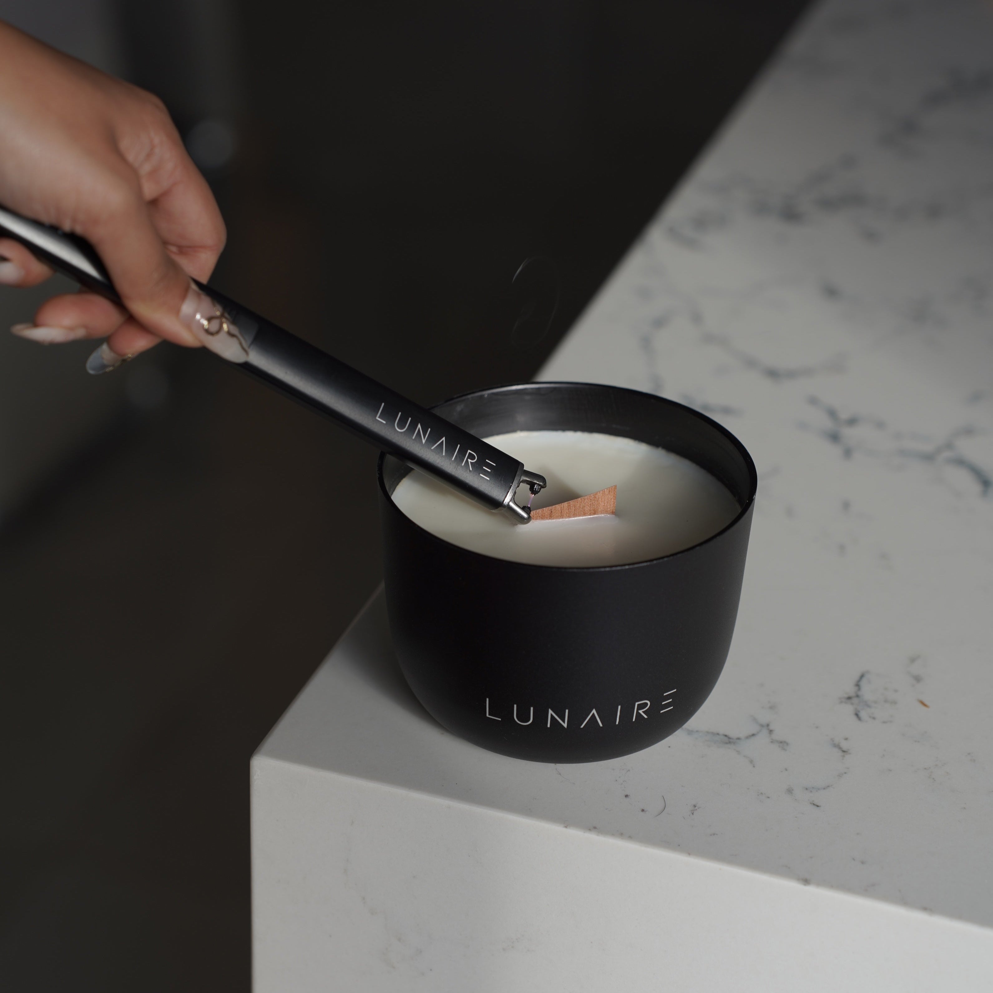 Black aluminium lunaire candle being lit by lunaire rechargeable lighter 