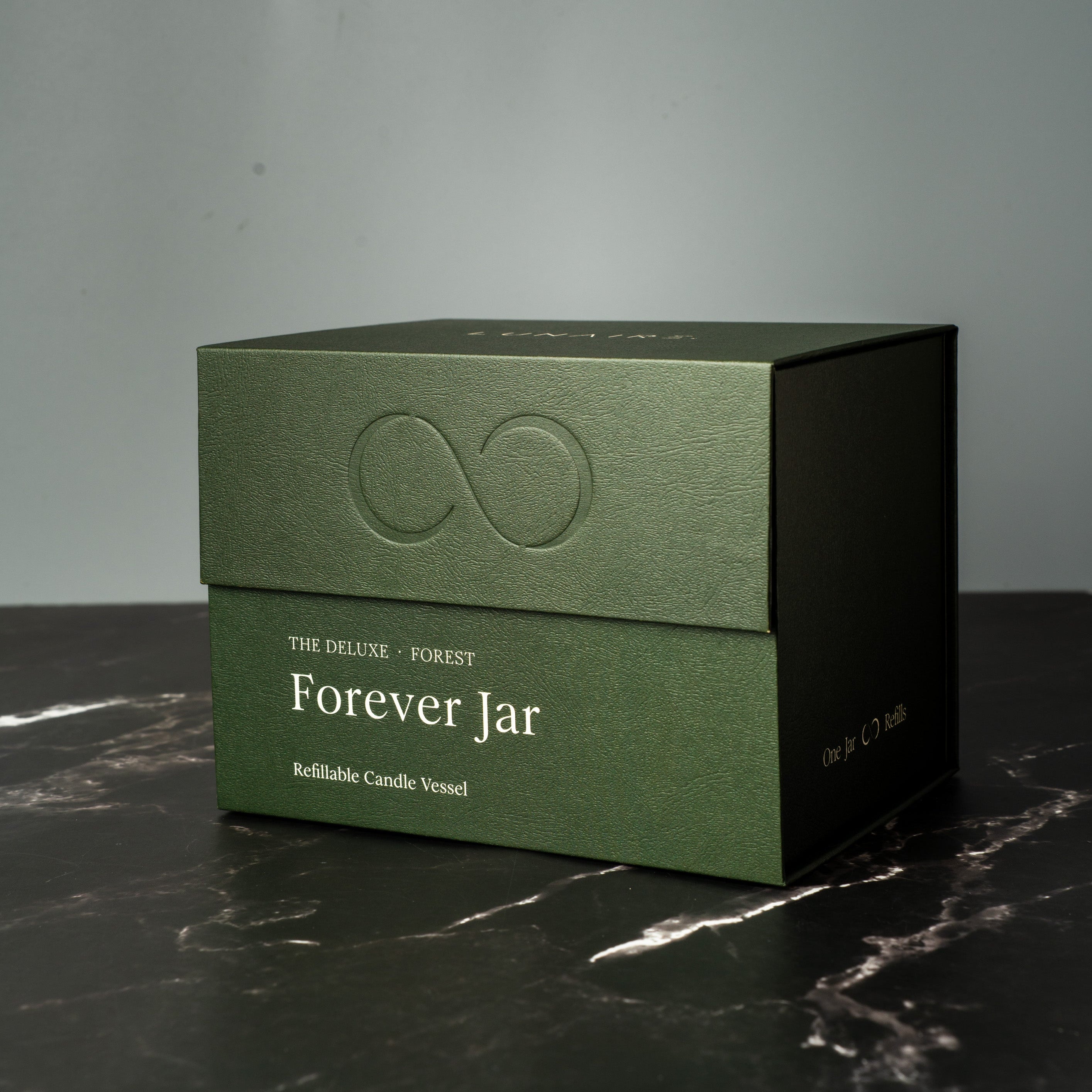 Green premium gift box labeled 'Forever Jar' on a dark surface with a gray background. Lunaire Refillable Candles. 