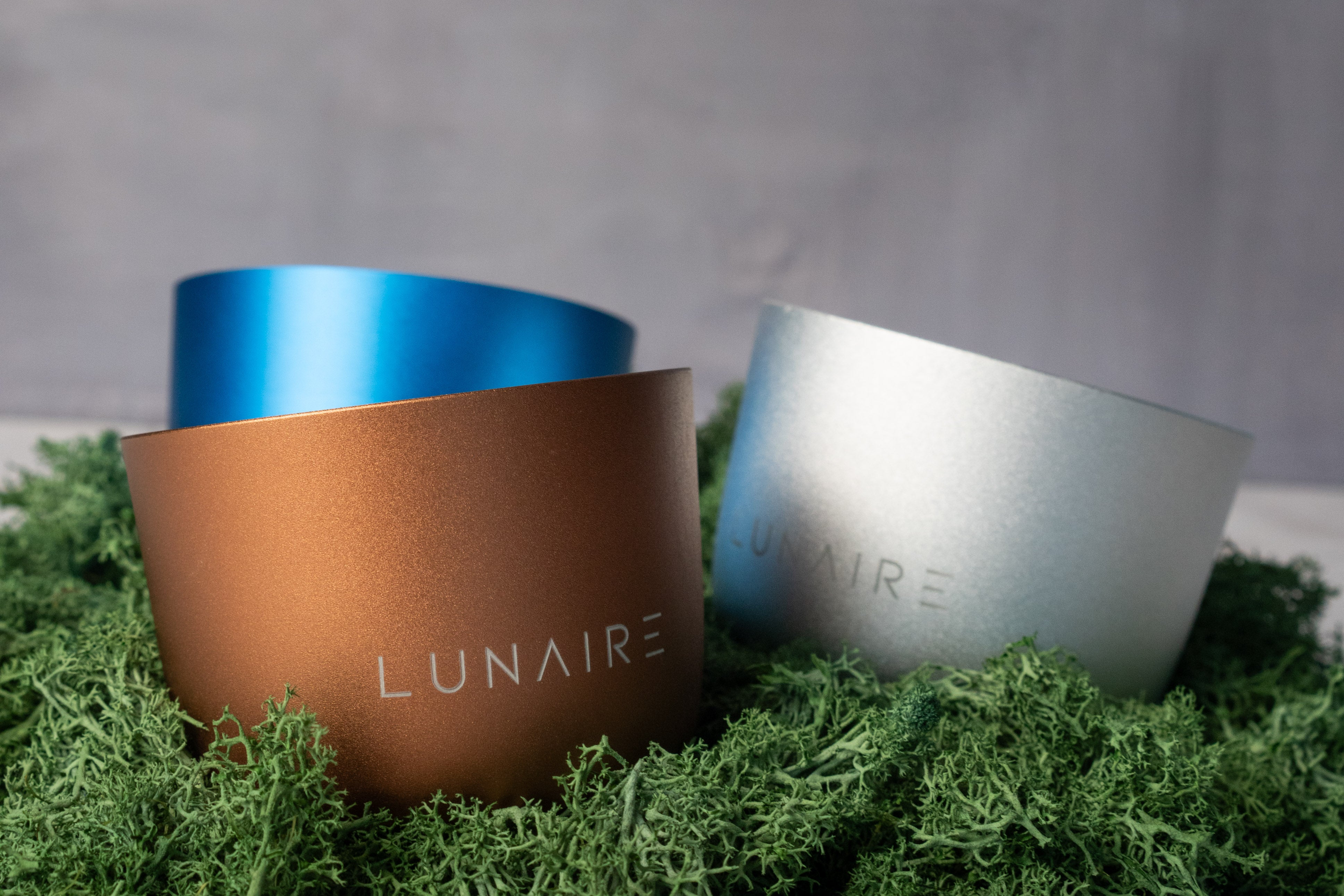 Lunaire aluminium Forever Jar candles on top of green grass. 