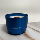 Blue candle with 'Queen Bee' branding on a light background