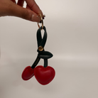 Cherry-shaped keychain held by a hand against a plain background