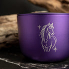 Purple aluminium candle with a horse design on a dark surface